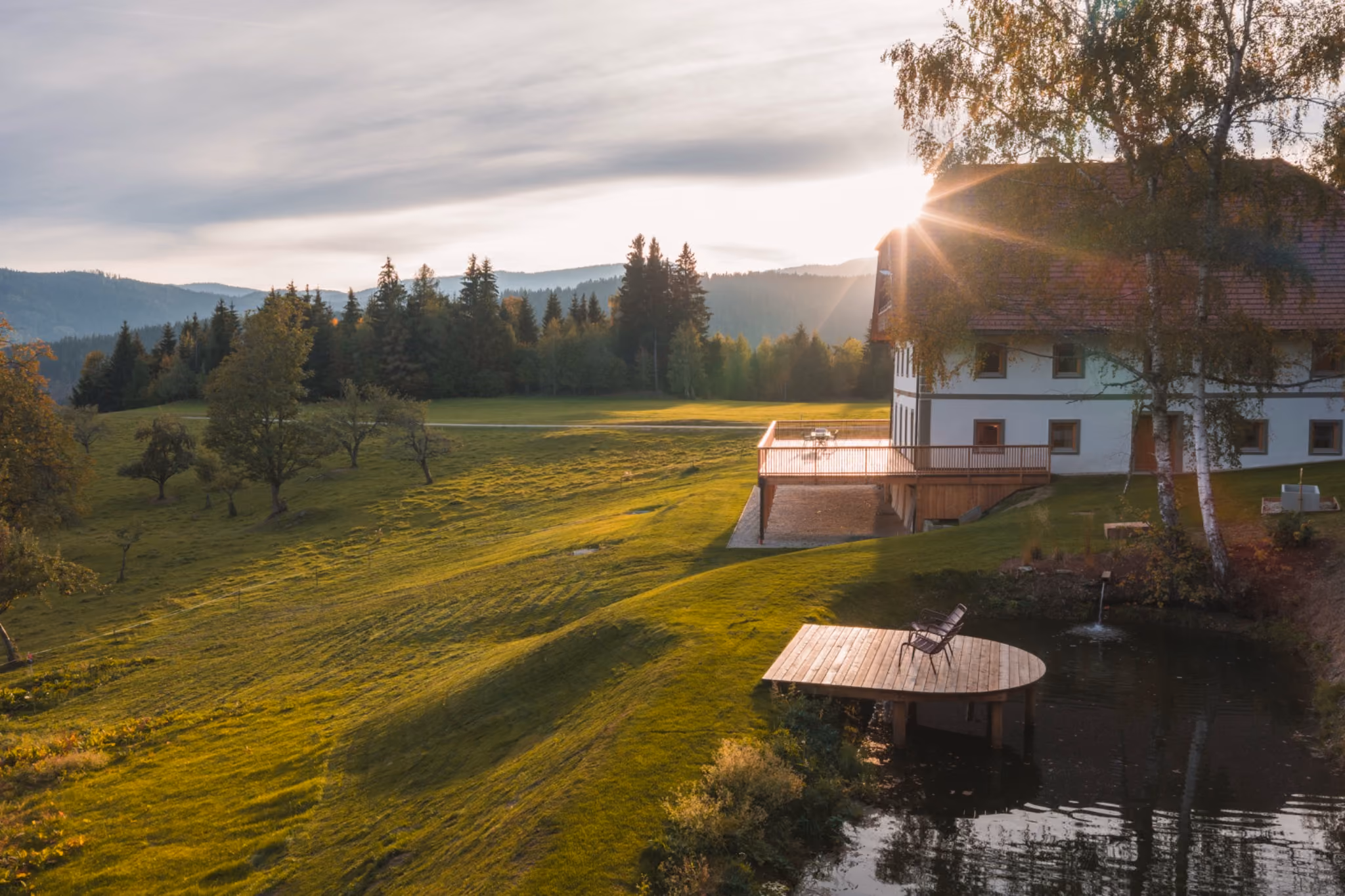 Der Teich mit Holzsteg vor dem Gregorhof im Licht der Abendsonne.