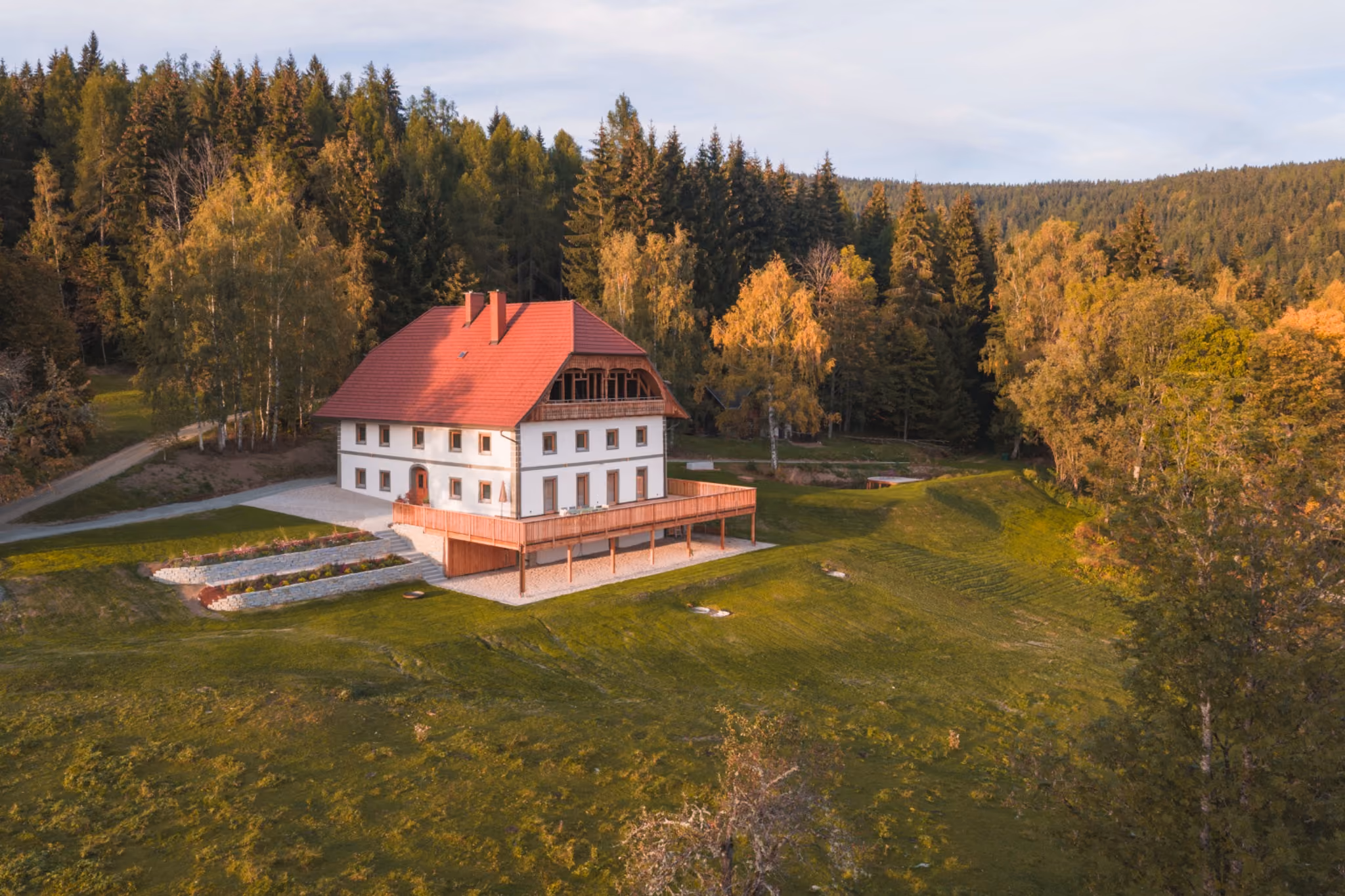 Luftaufnahme des Gregorhofs zwischen Nadelwald und herbstlich gefärbten Laubbäumen.
