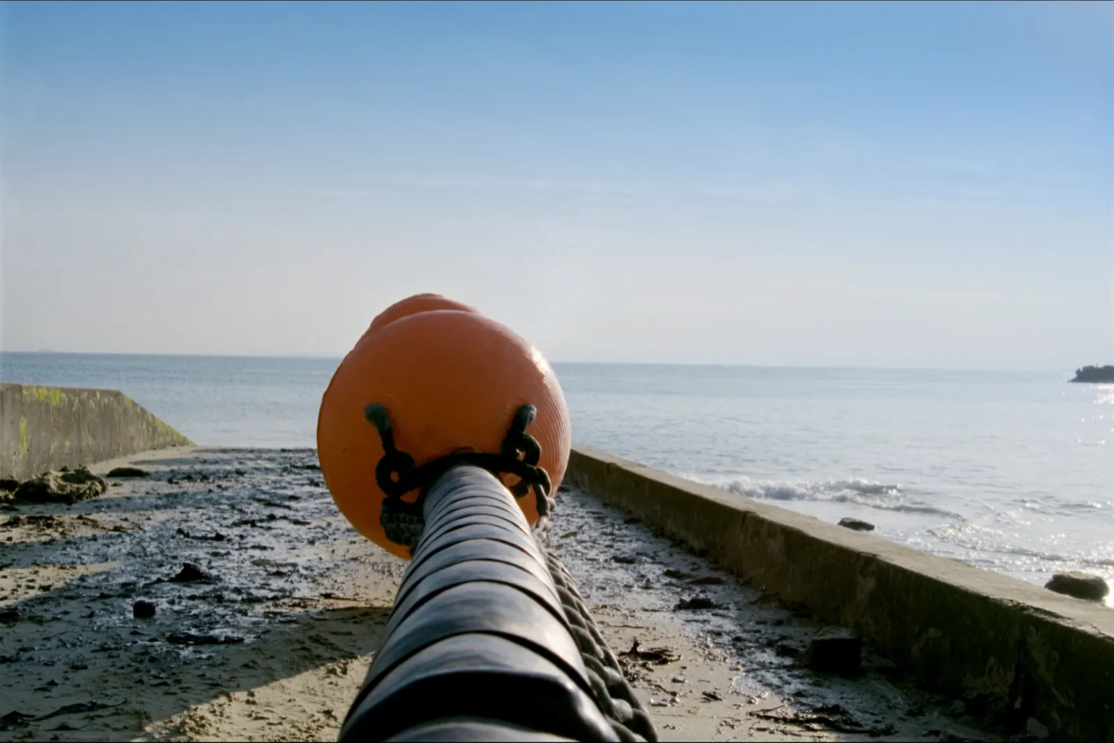 Subsea cable coming ashore on a bright beach, orange markers along its route on the west coast of Ireland