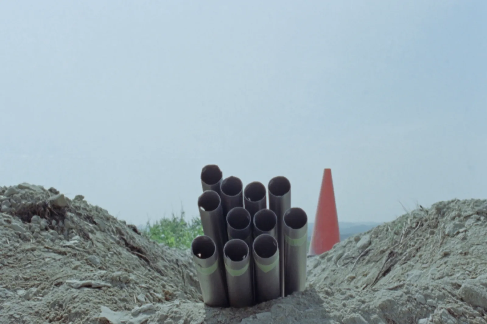 Fibre duct trench beside a road under an open daylight sky, orange roadworks equipment alongside in Serbia