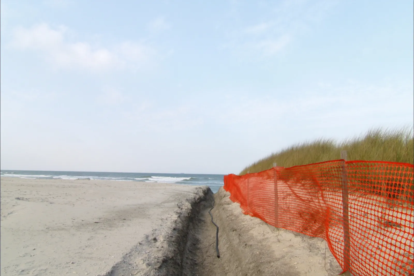 Daylight Atlantic shore, cable landing works with an orange marker on the New Jersey shore