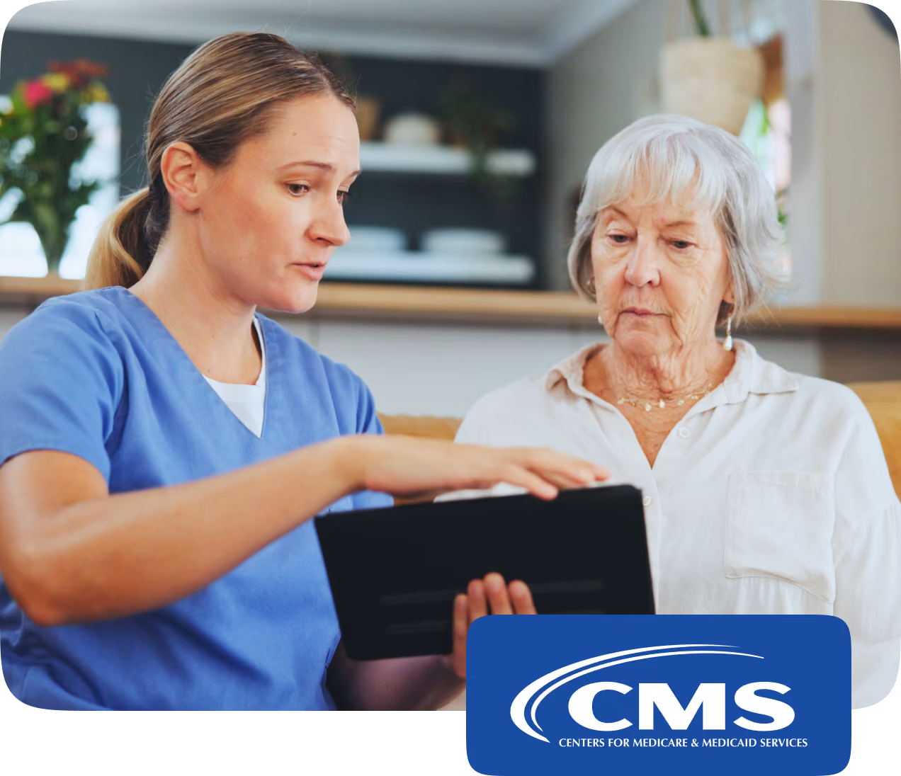 A female healthcare worker in blue scrubs shows information on a digital tablet to an elderly woman with gray hair, both sitting indoors with a blurred background, accompanied by the CMS logo for Centers for Medicare & Medicaid Services.