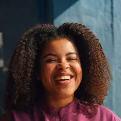 Smiling woman with curly hair in a purple top