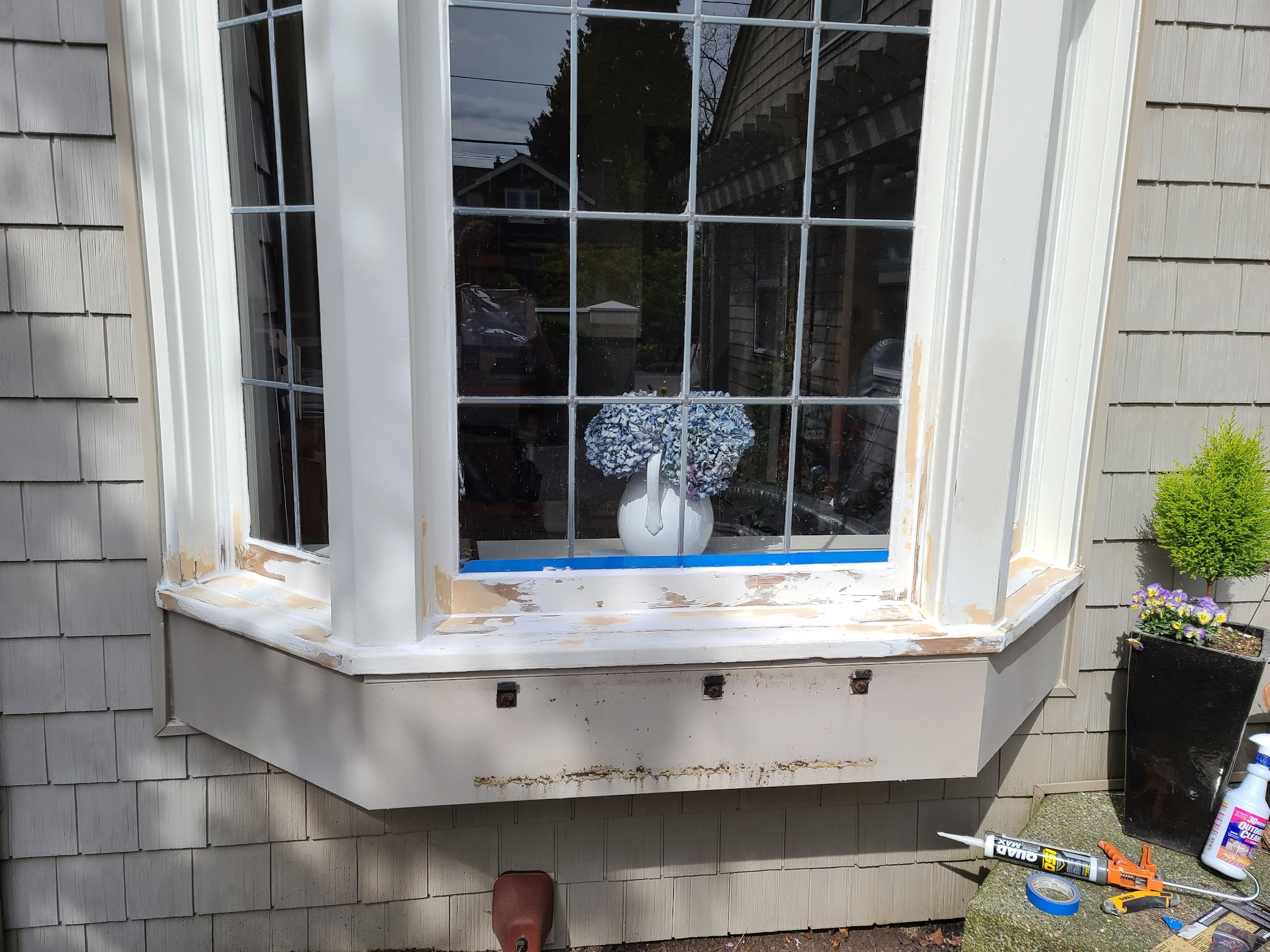 Exterior bay window with prepped, sanded, and filled wood trim undergoing rot repair.