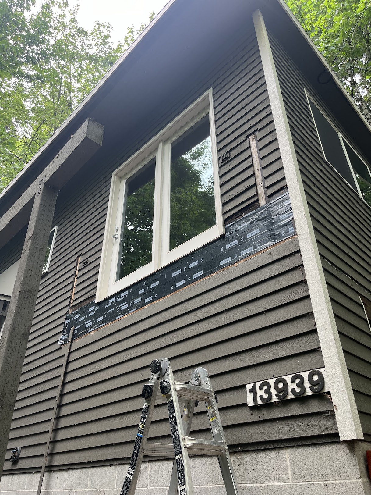 Dark grey home showing black waterproof flashing installed beneath a upper-story window during repairs.