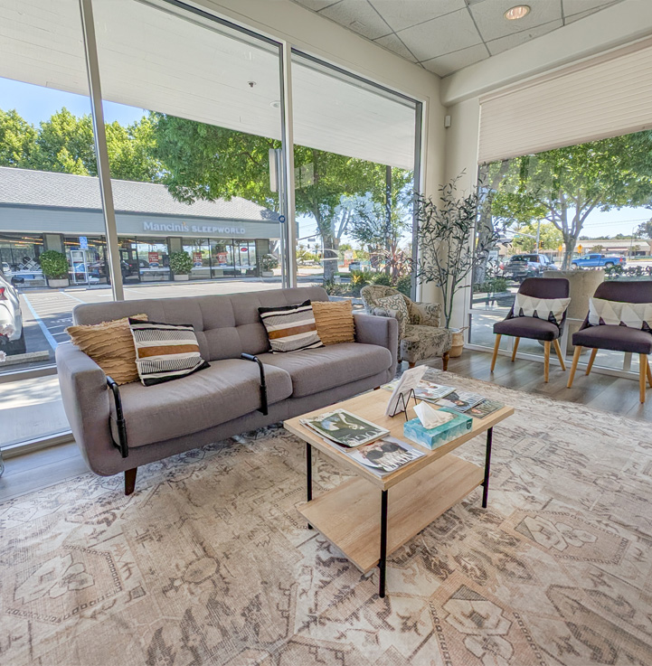 Bright patient waiting lounge with sofa and large windows at Genuine Care Dental, dentist in Saratoga, CA