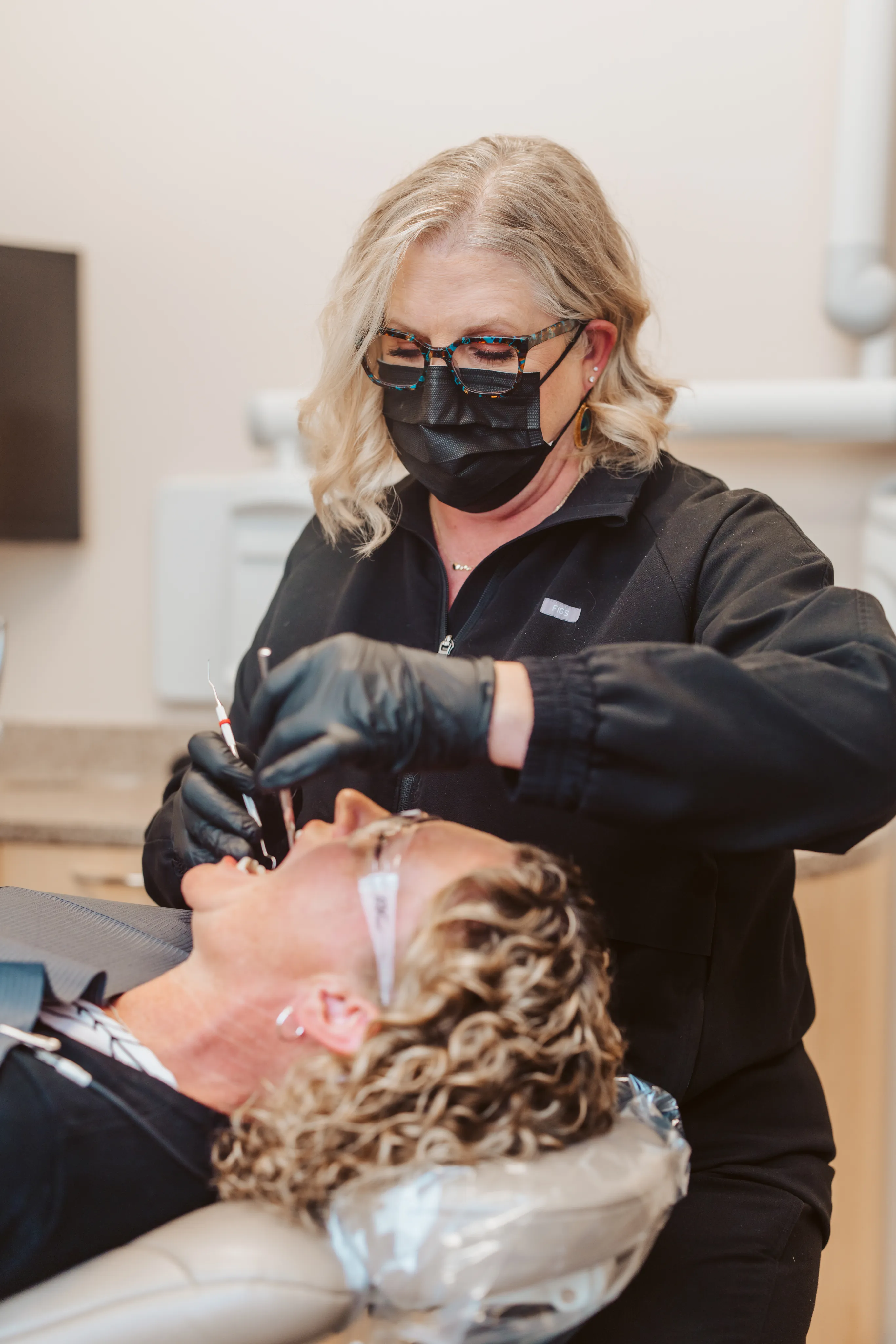 Masked clinician treating a reclined patient for cosmetic dentistry