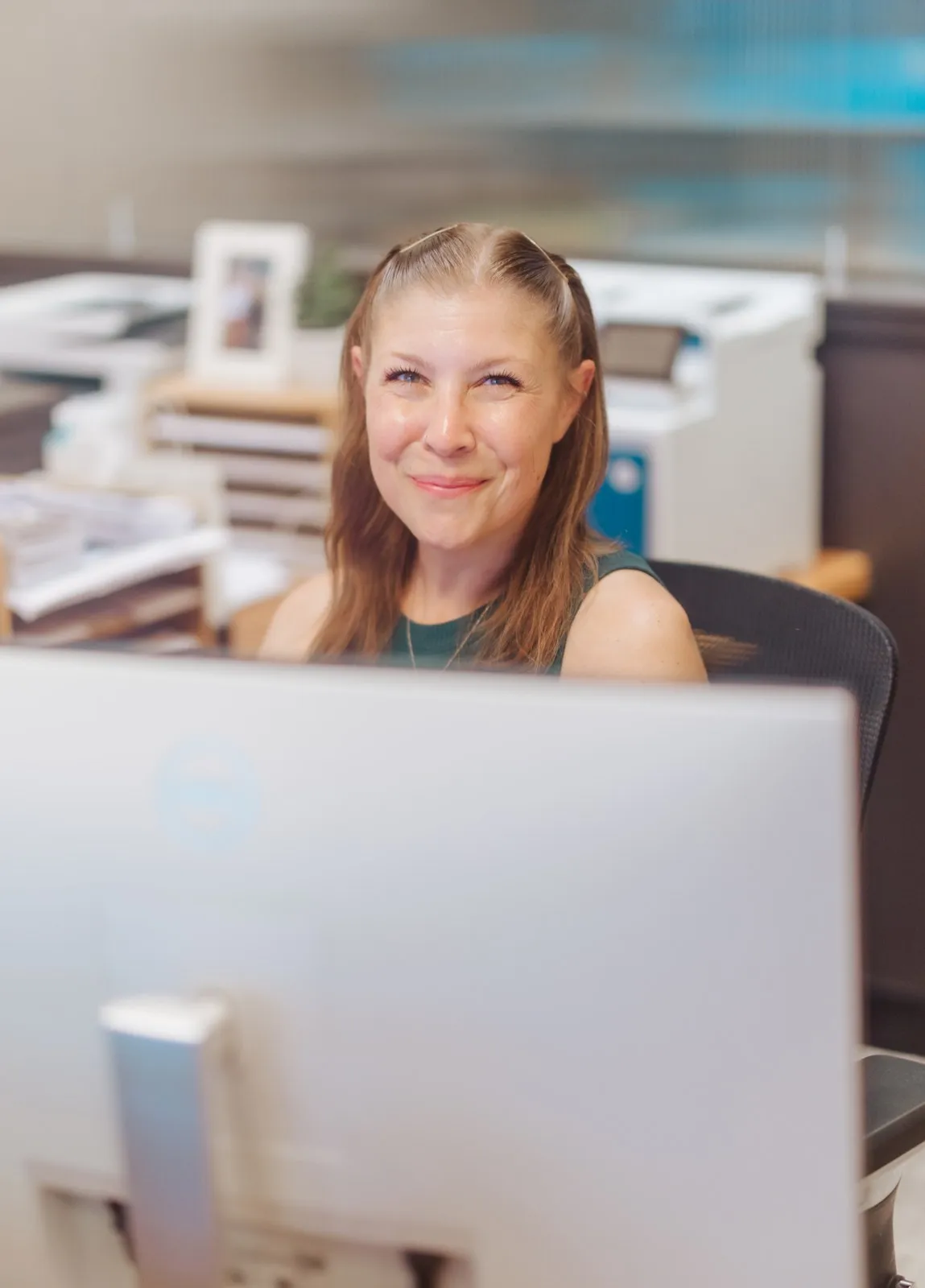 Smiling J & D Dental team member seated at the front desk computer