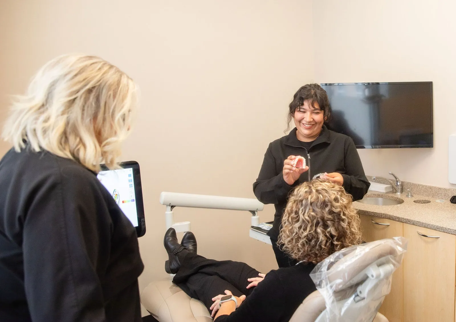 J & D Dental team members reviewing care with a patient in a treatment room