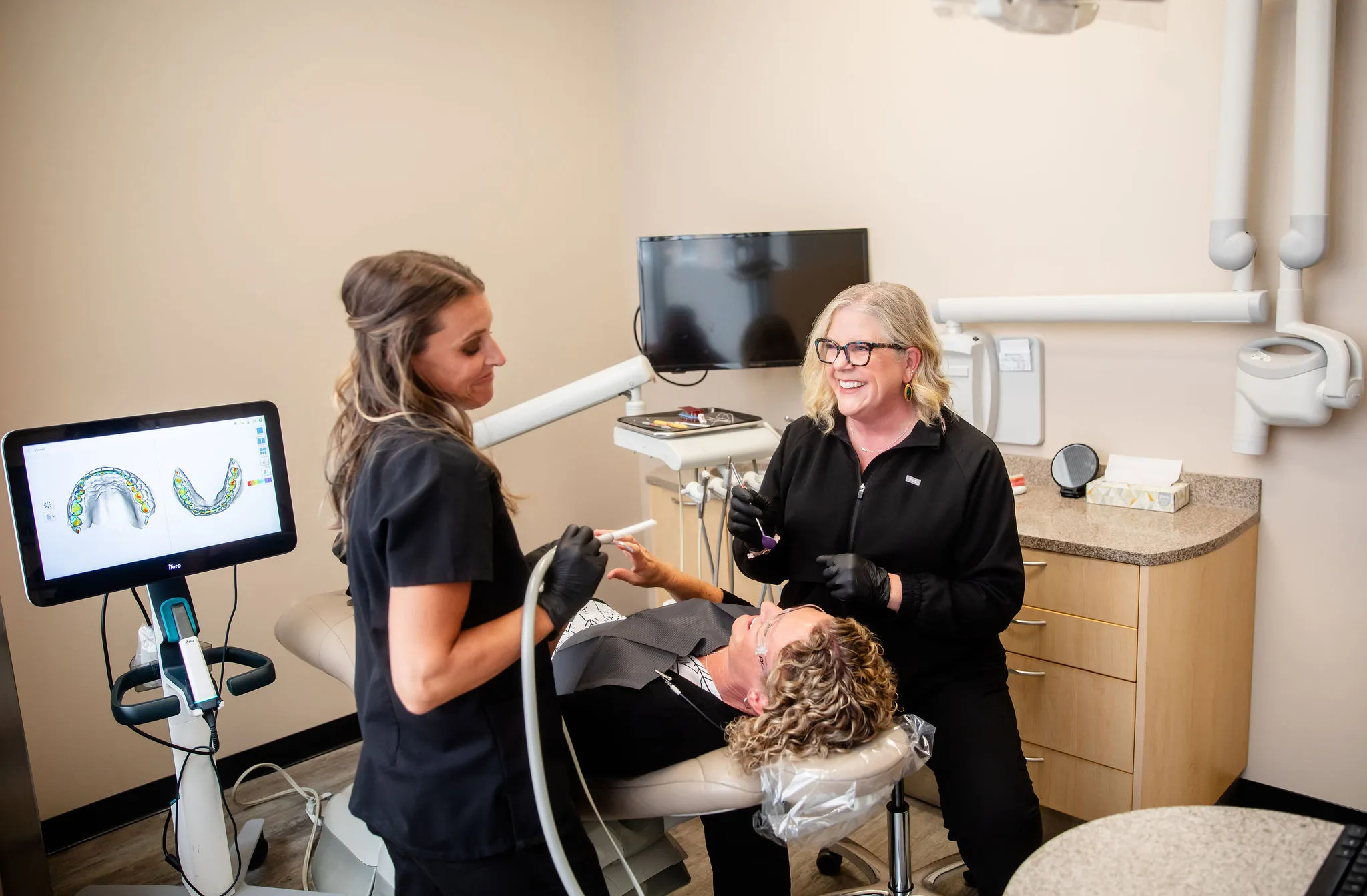 Dr. Herbert talking with a patient while a team member holds a digital scanner.