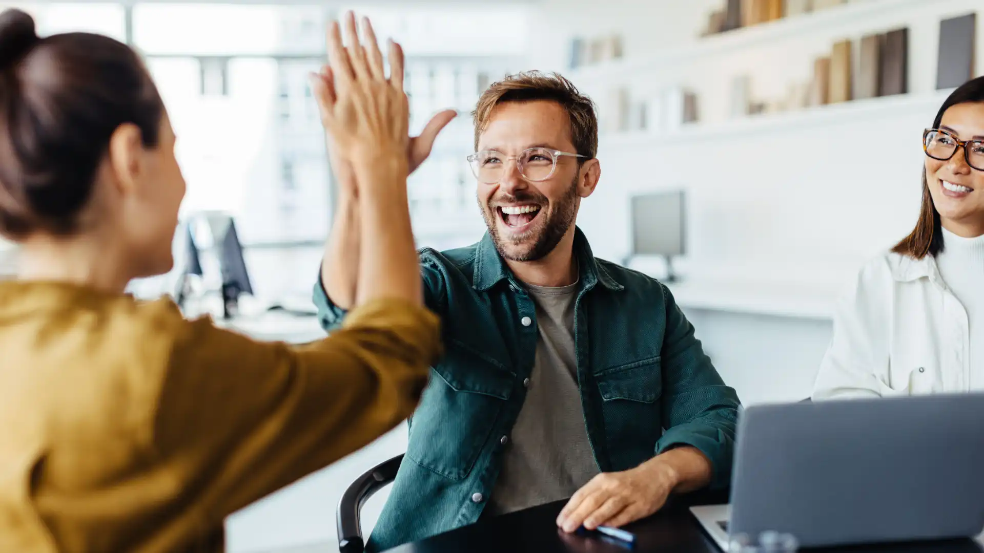 Team im Büro klatscht ab und freut sich über einen gemeinsamen Projekterfolg