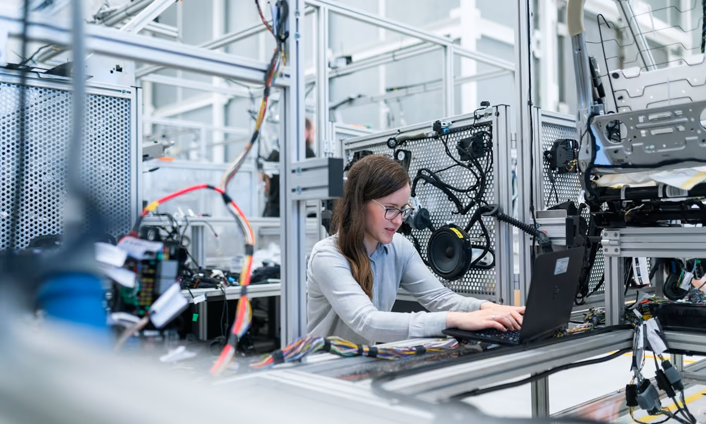 Engineer working on a laptop in a robotics hardware lab.