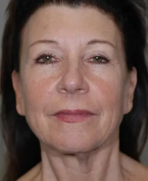 Close-up portrait of a middle-aged woman with light makeup and dark hair against a neutral background.