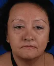 Close-up of a middle-aged woman with short dark hair and neutral expression against a dark blue background.