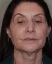Close-up of a middle-aged woman with dark hair, wearing small hoop earrings, eyes partially closed.