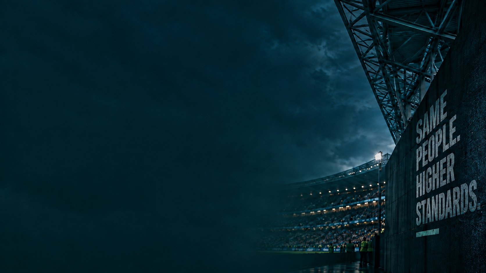 A dark stadium wall reading Same People Higher Standards, floodlights beyond