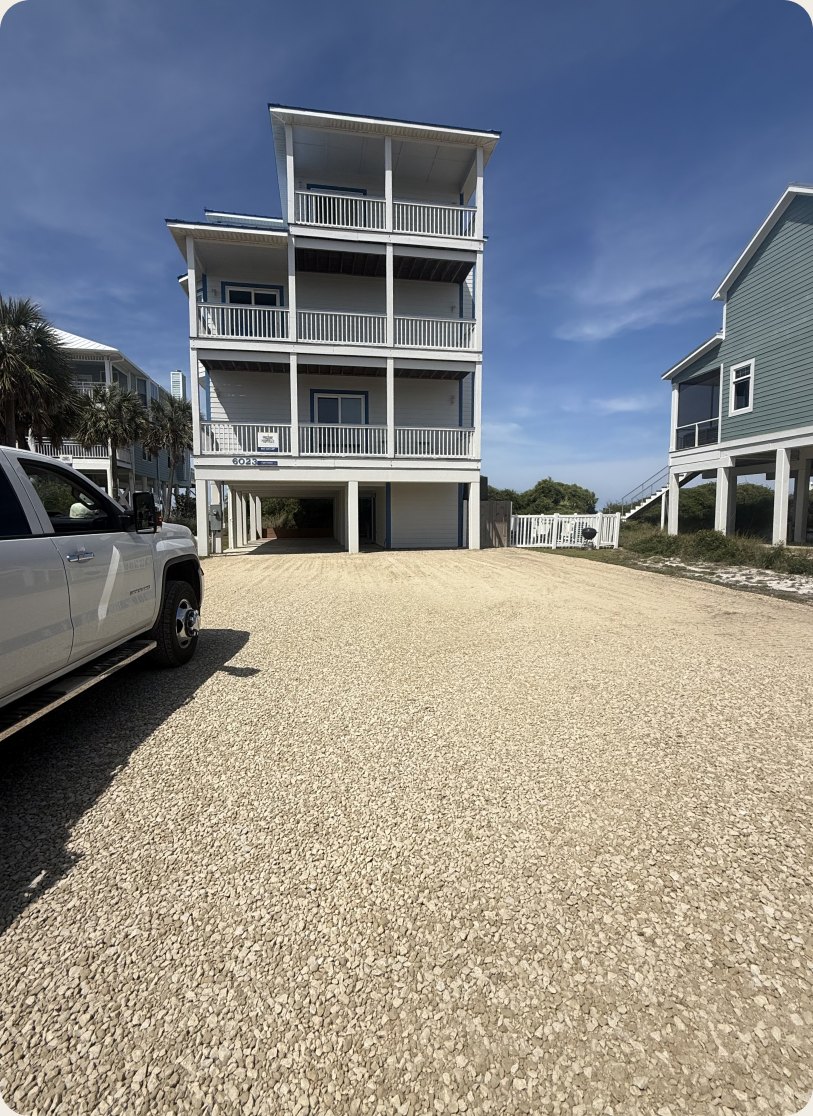 Finished gravel driveway beside a raised coastal home