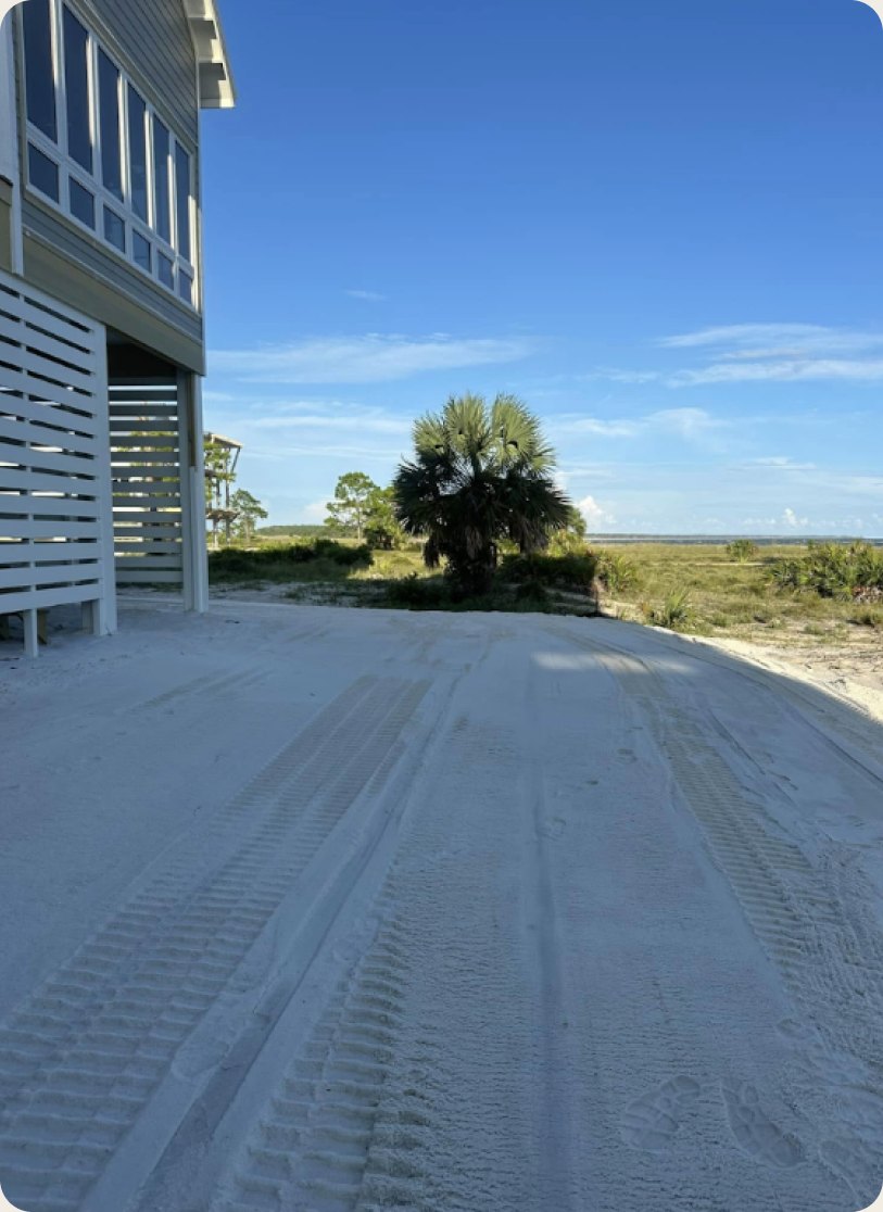 Compacted shell driveway running past a raised home toward open marsh