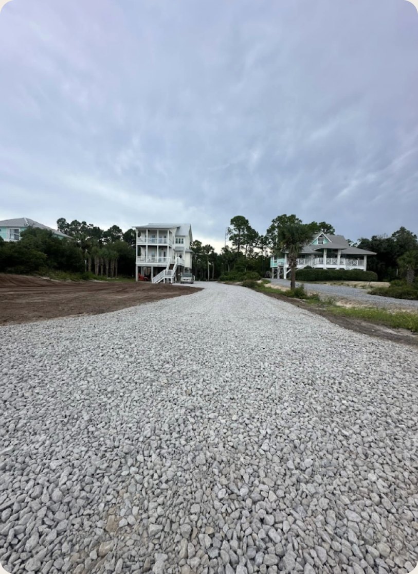 Wide gravel driveway leading to two raised coastal homes