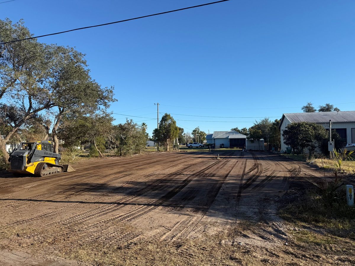 Skid steer clearing and leveling a lot beside a rural Florida property