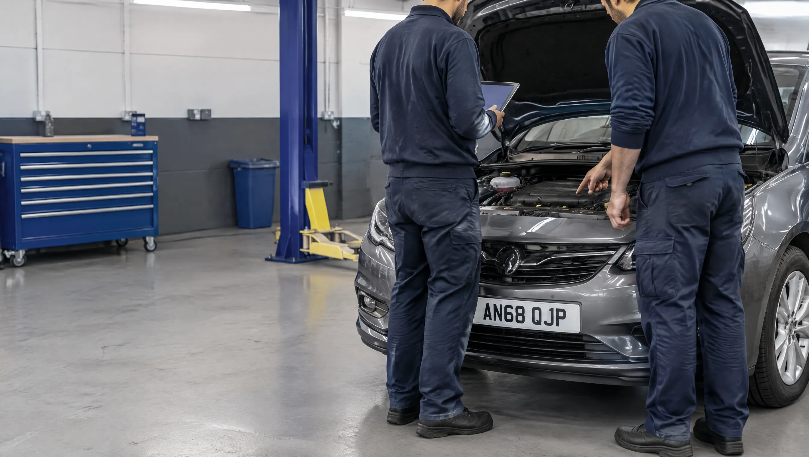 Illustrative image of technicians discussing a vehicle inspection.