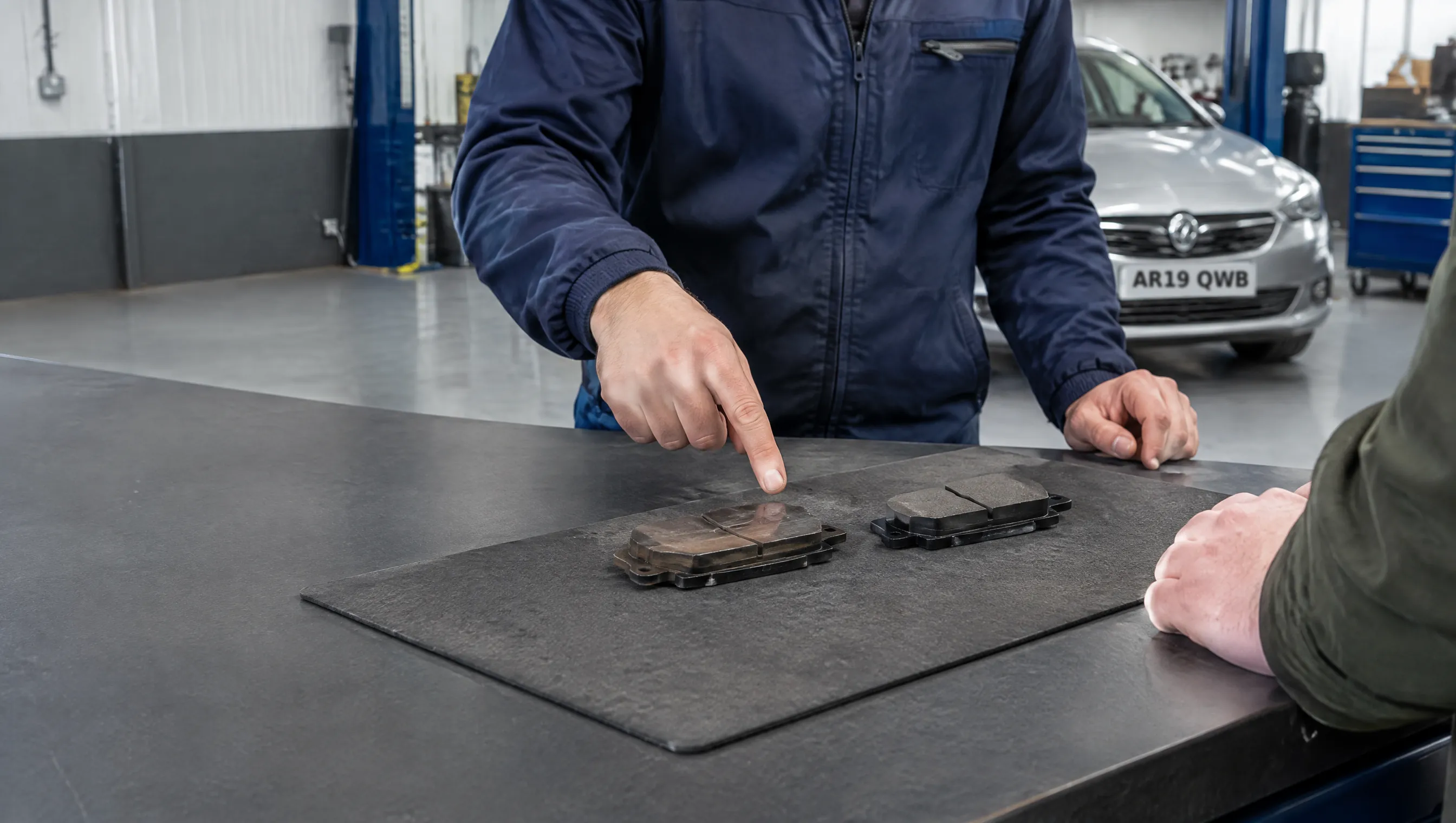 Illustrative image of a technician explaining brake-pad wear to a customer.