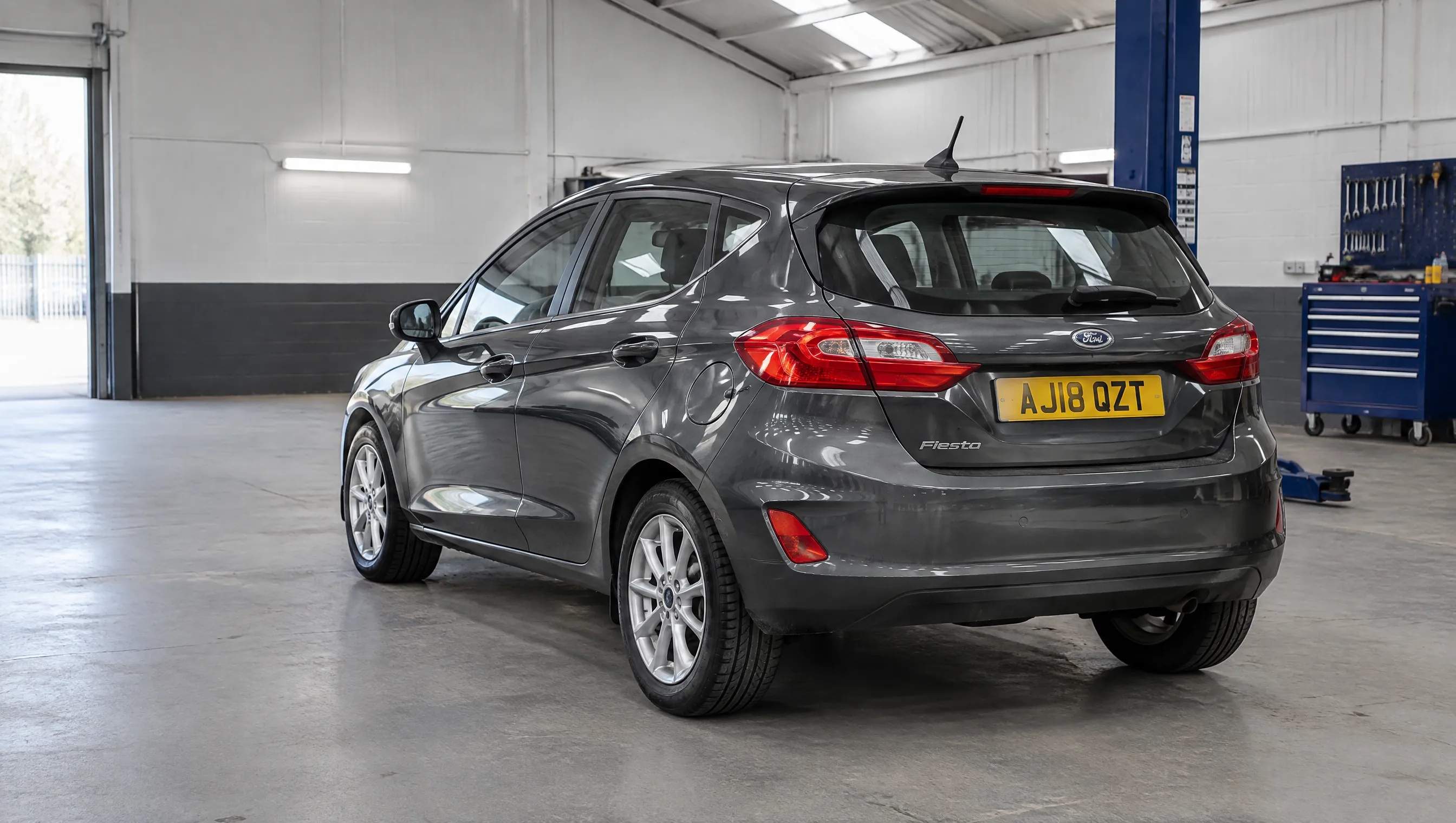 Illustrative image of a compact hatchback ready for inspection in a workshop.