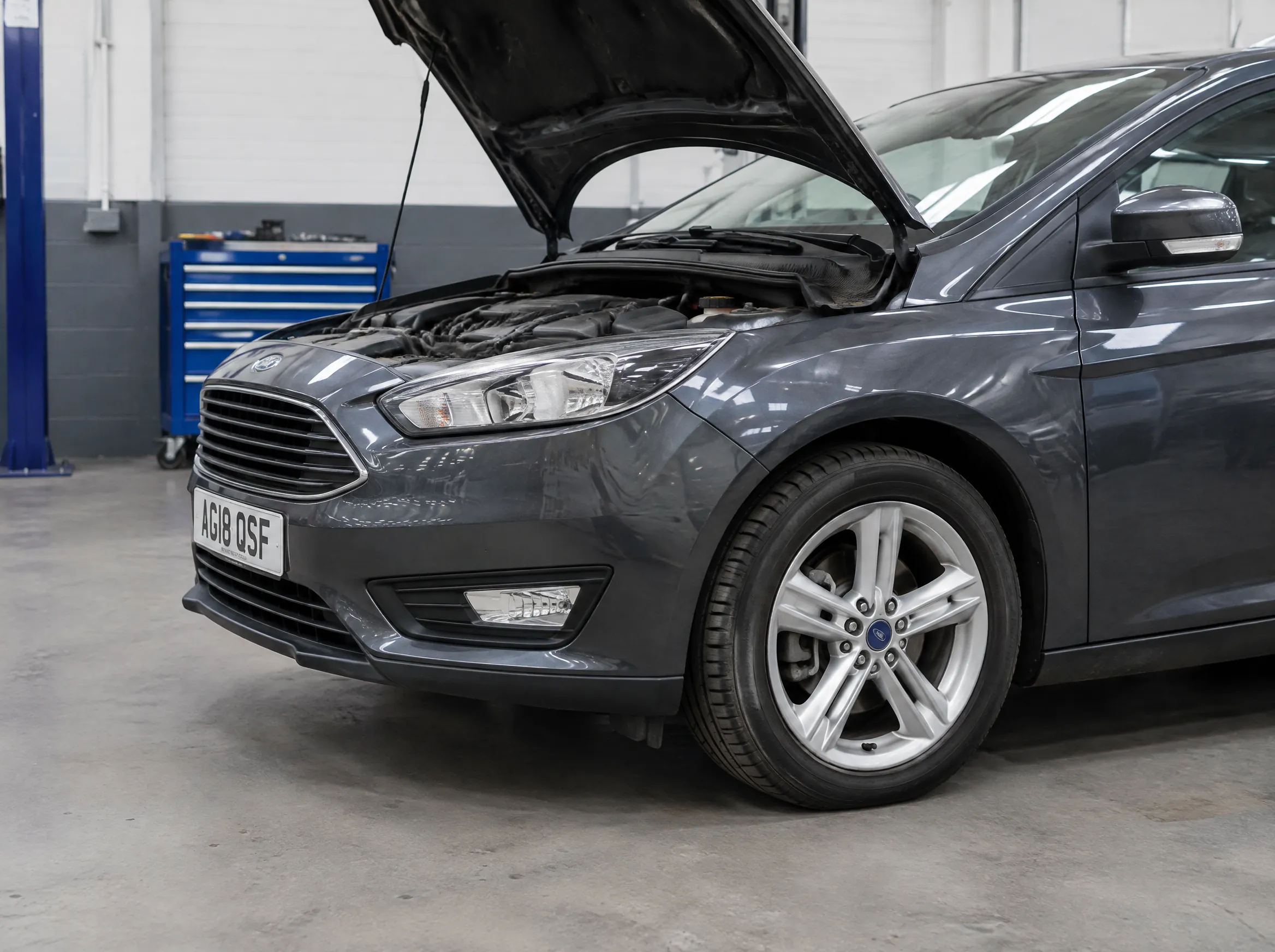 Illustrative detail of a car in a modern vehicle workshop.