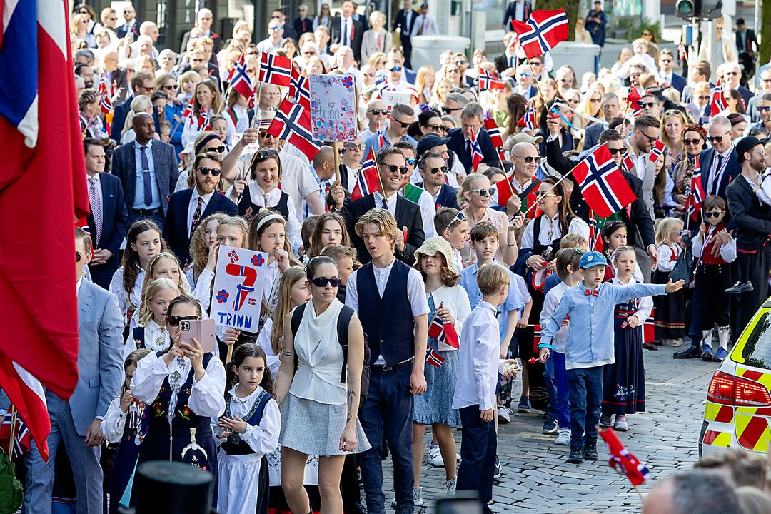Barn og voksne med norske flagg i en 17. mai-prosesjon i Bergen.