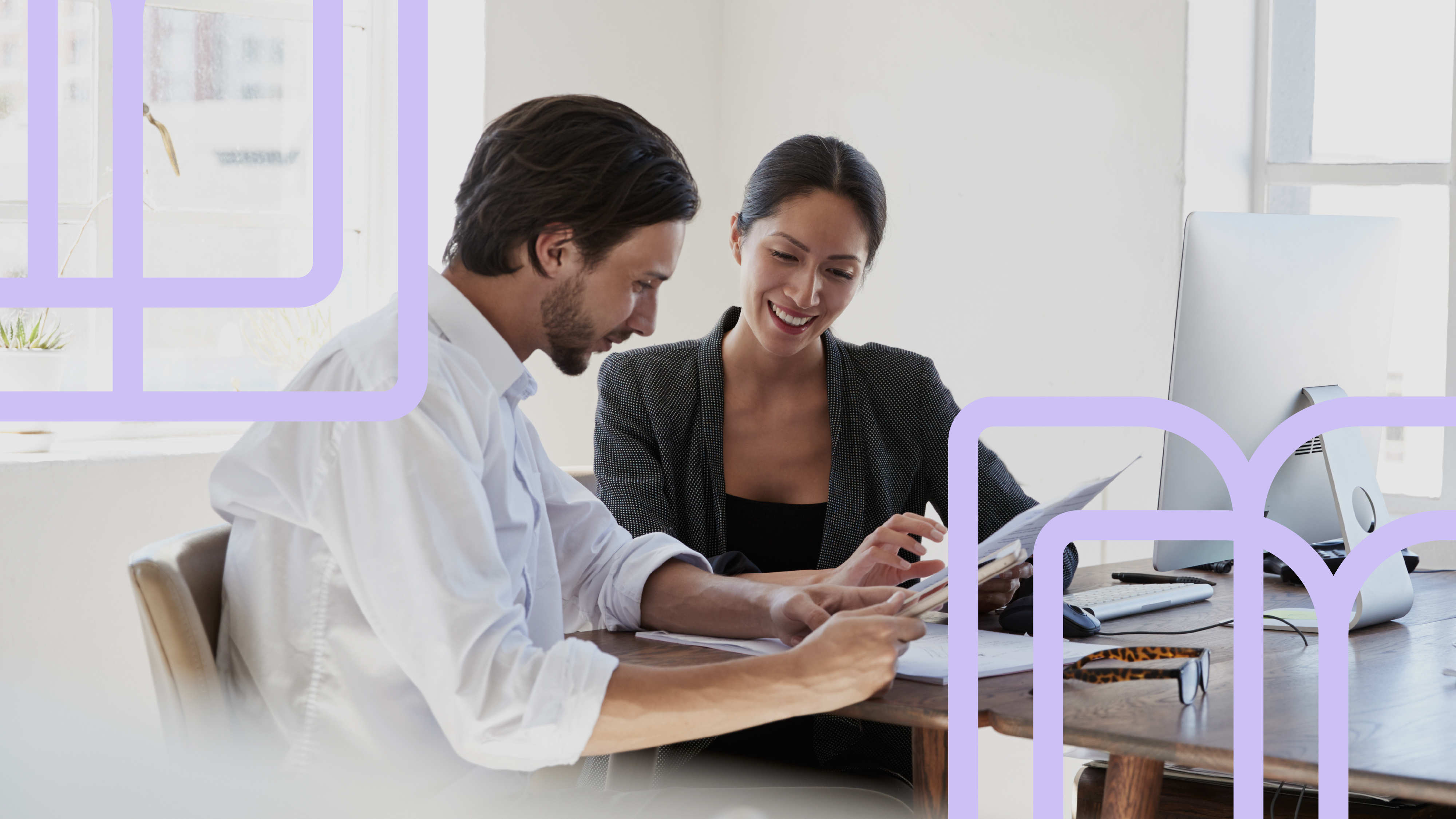 Two people collaborating over a laptop at an office table