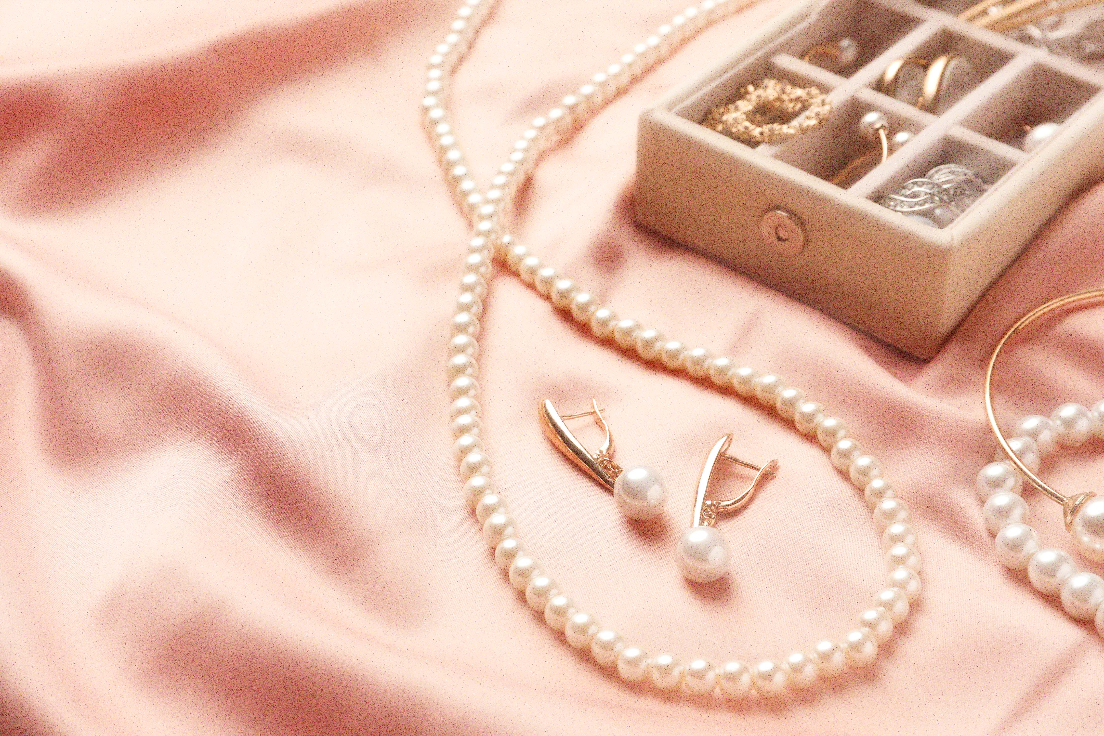 Pearls, gold earrings, and rings in a cream box