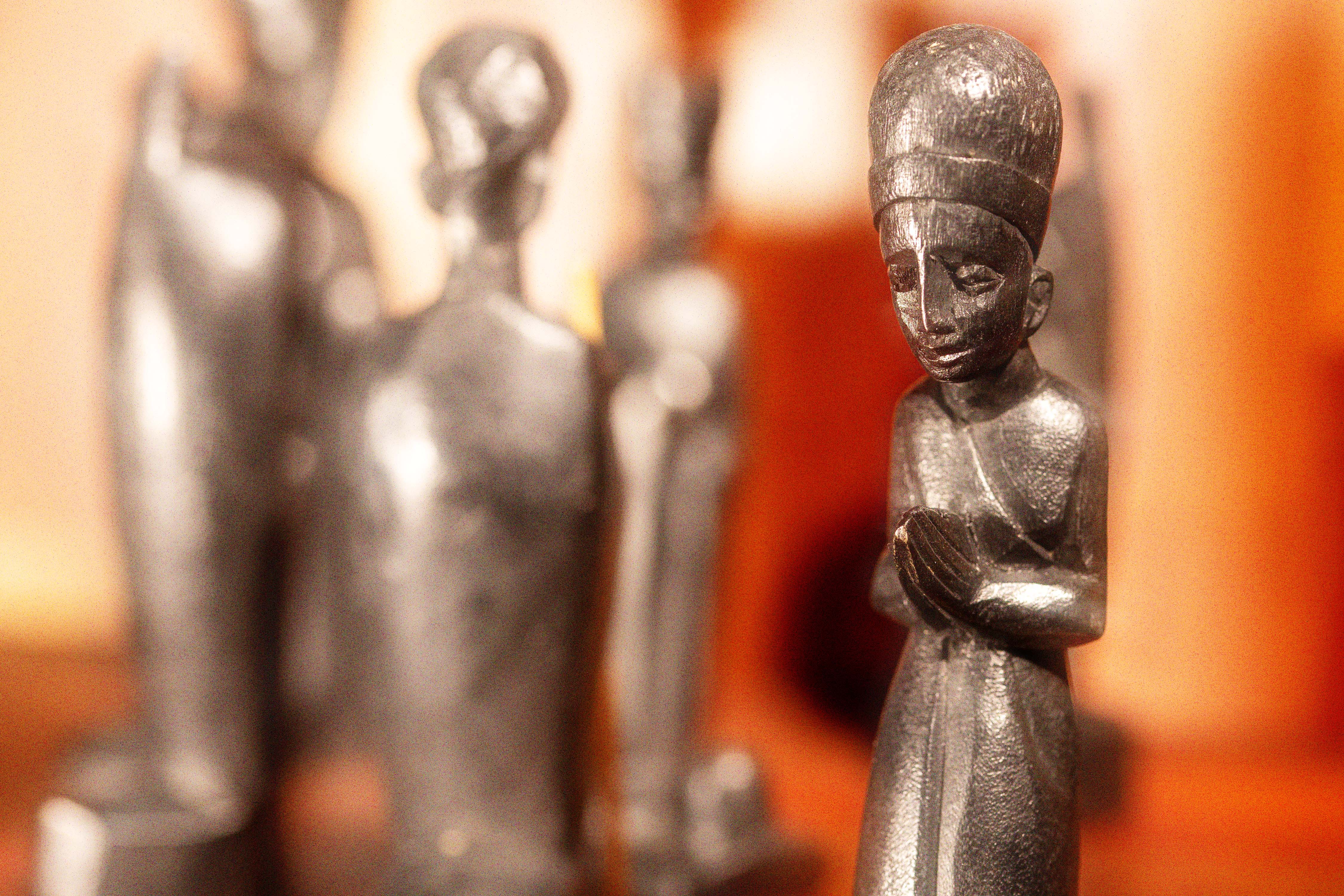 Dark metal figurines with hands pressed together