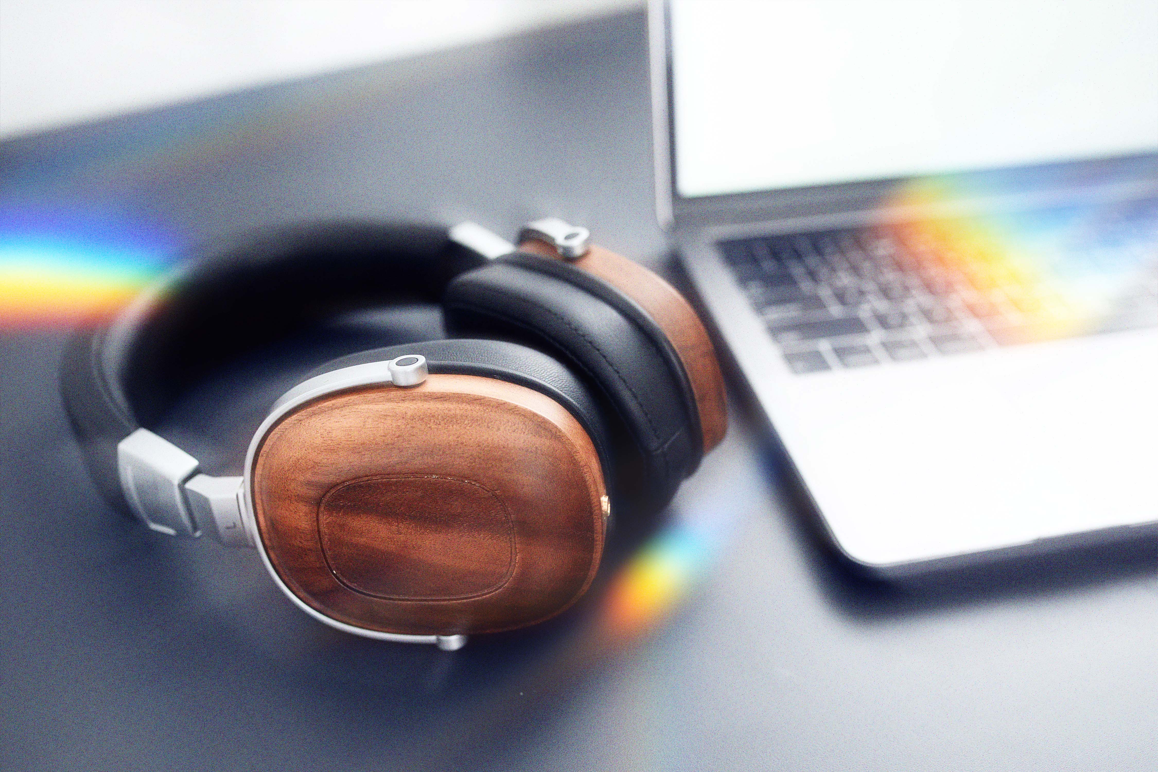 Wooden headphones beside an open laptop