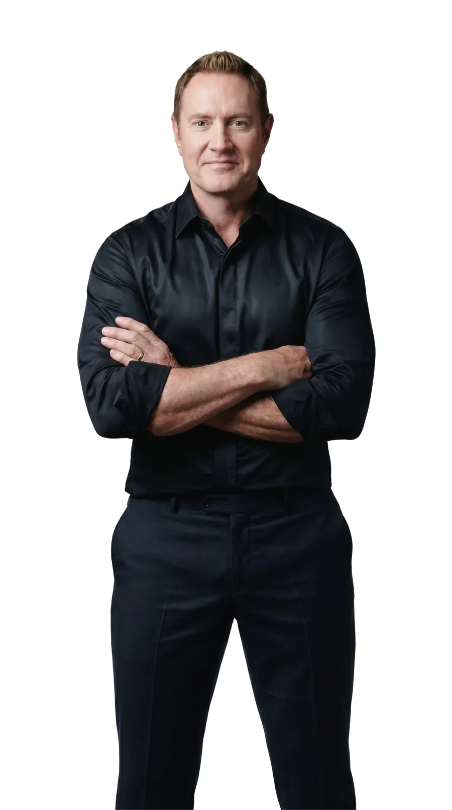 Darren Hardy standing full length with arms crossed in front of a wall of SUCCESS magazine covers