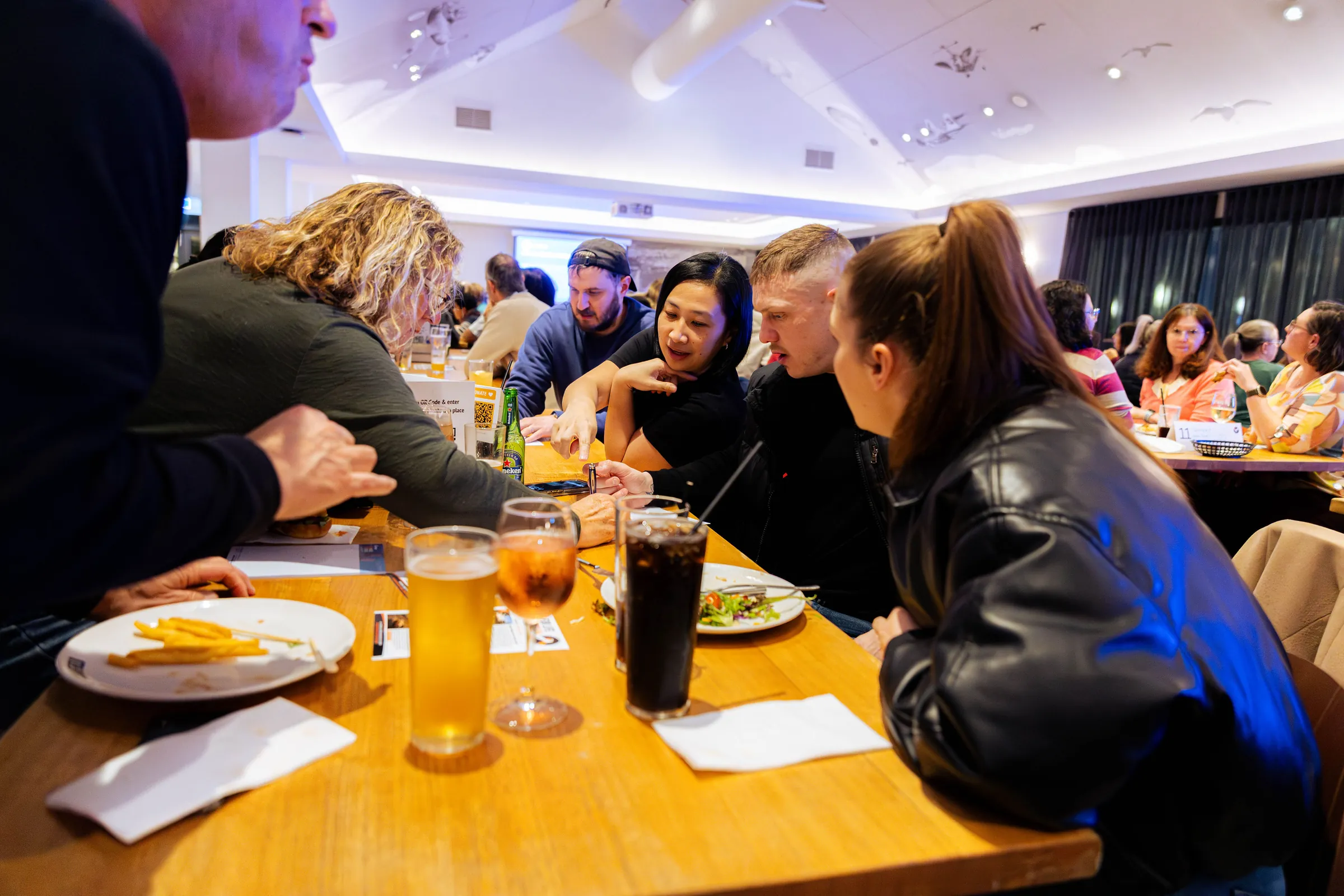 Guests talking around a table at the Armed For Life quiz night at The Hall, The Camfield, Burswood, photographed by Growth Concept Media.
