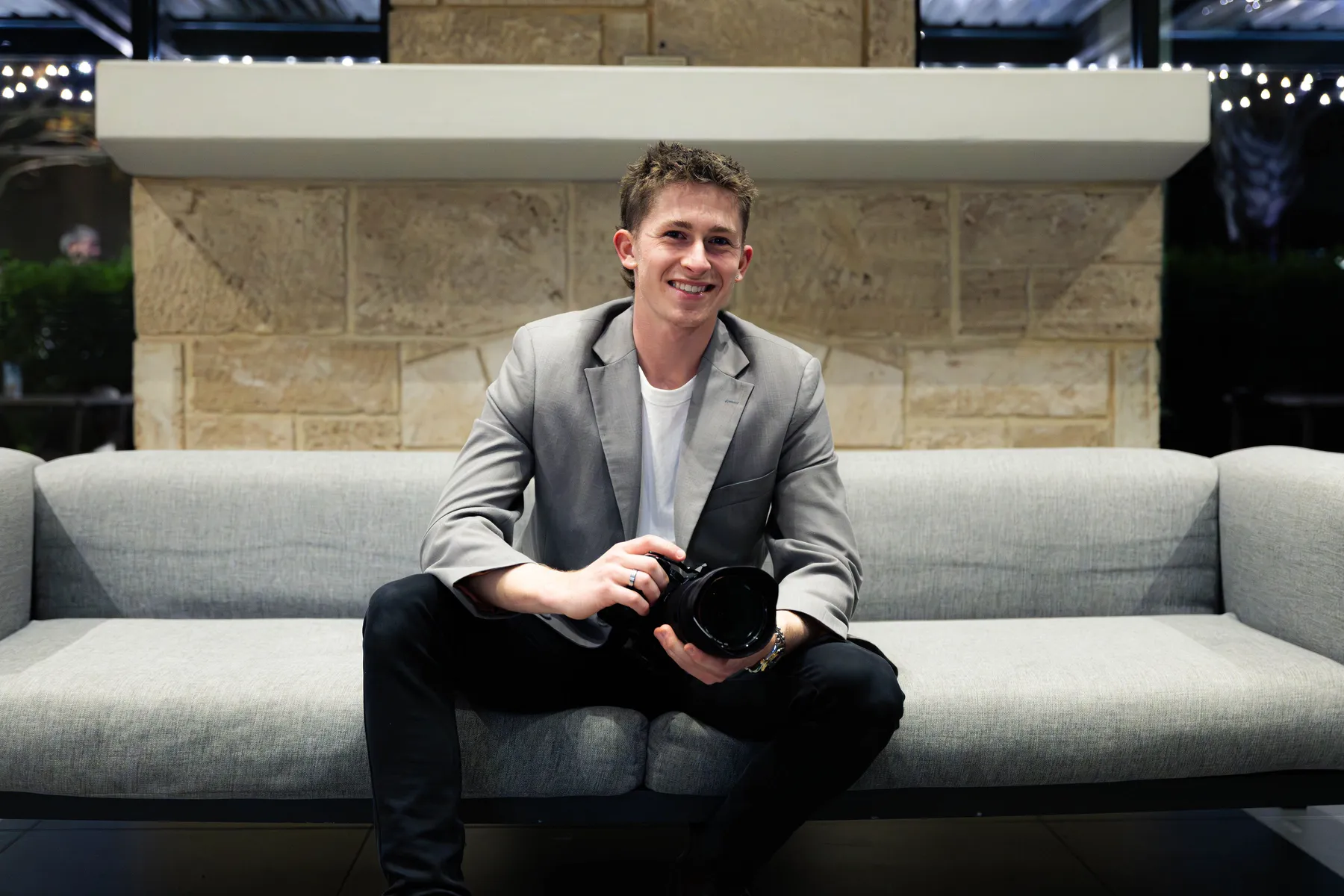 Keoni Upton seated on a sofa with a camera during a Perth portrait session.