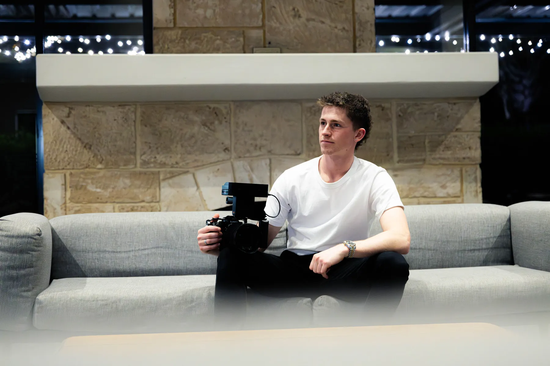 Keoni Upton on a sofa with a cinema camera during a Perth portrait session.