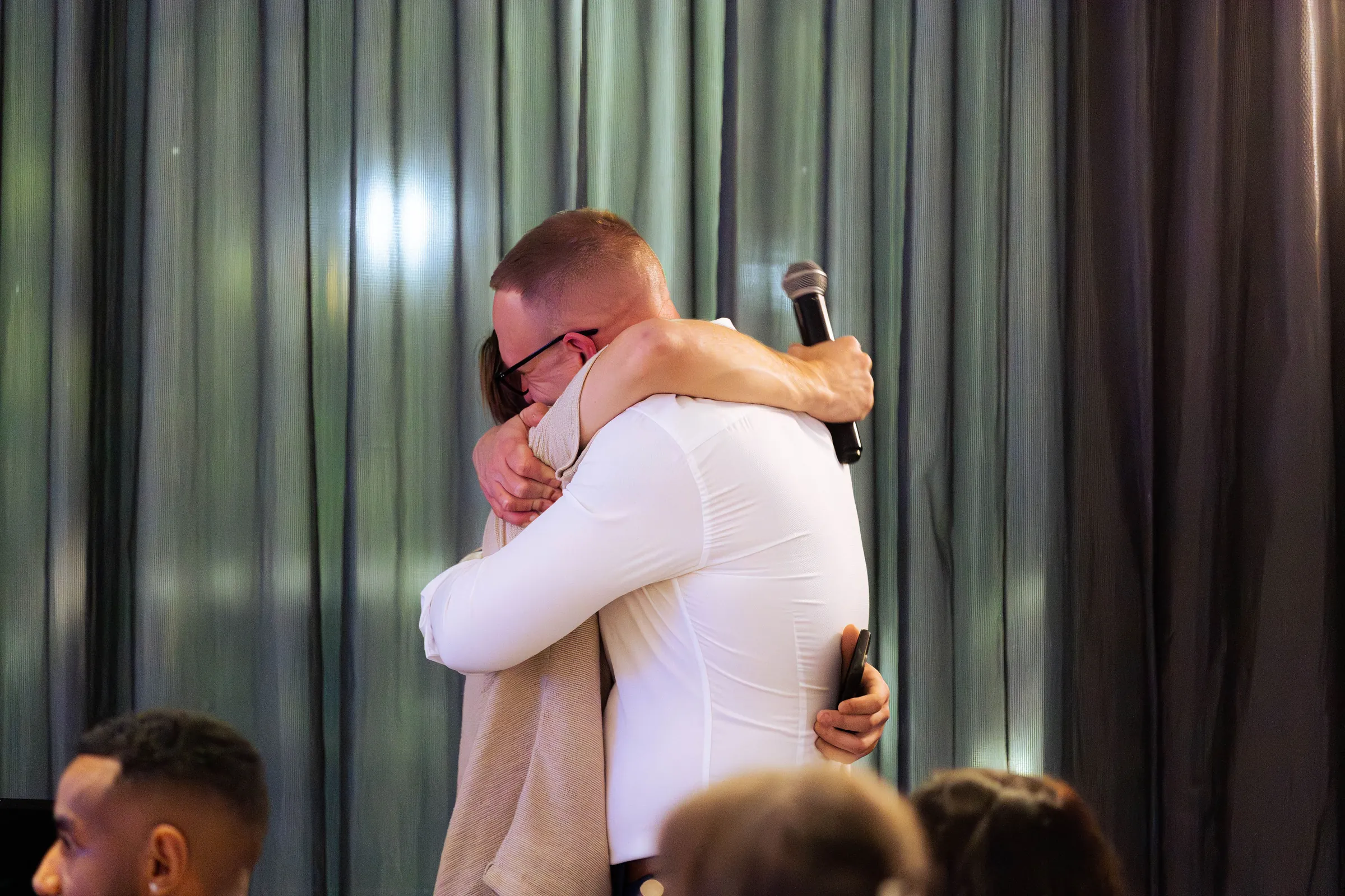 Two guests hugging on stage at the Armed For Life quiz night at The Hall, The Camfield, Burswood.