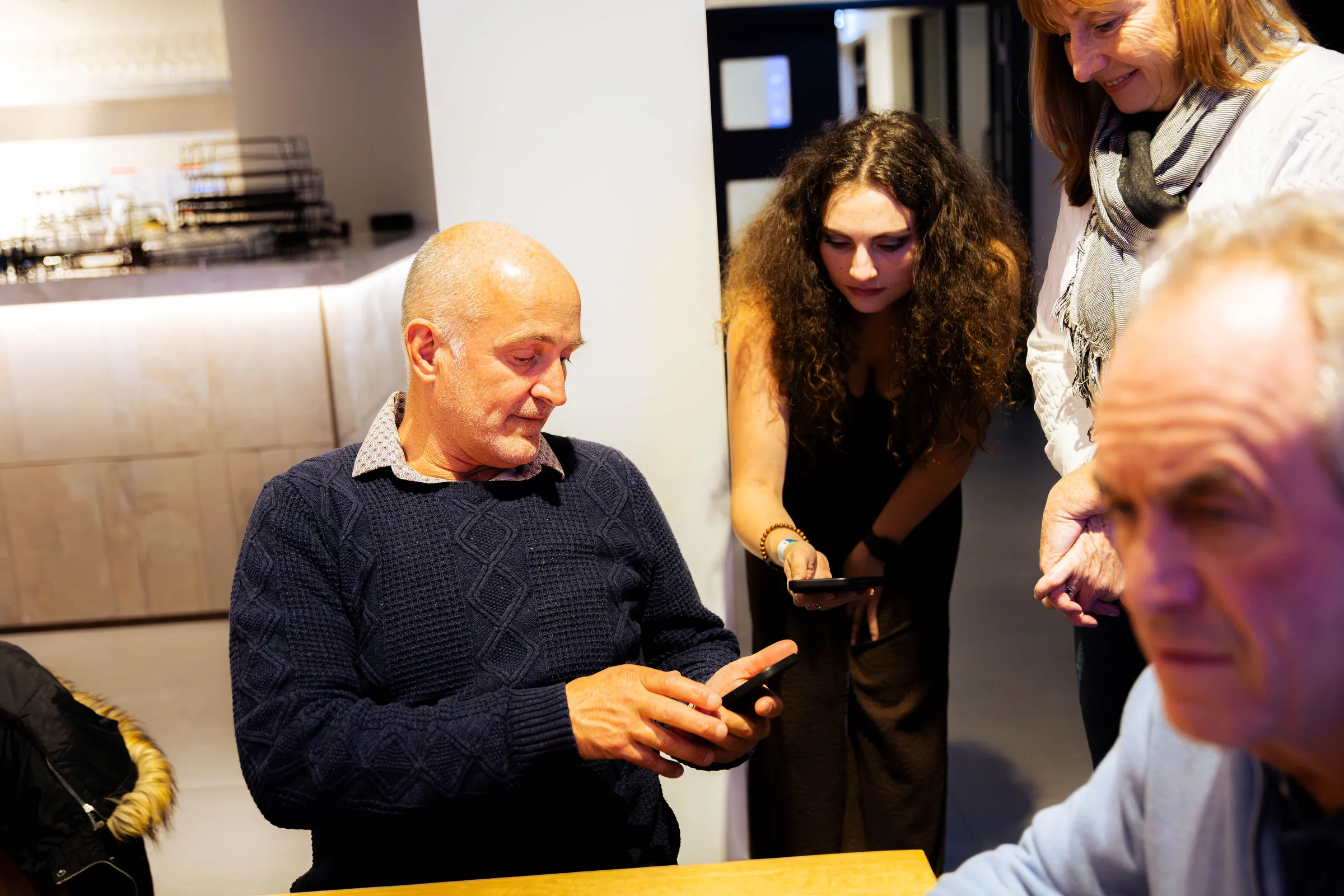 Guests looking at a phone together at the Armed For Life quiz night at The Hall, The Camfield, Burswood.