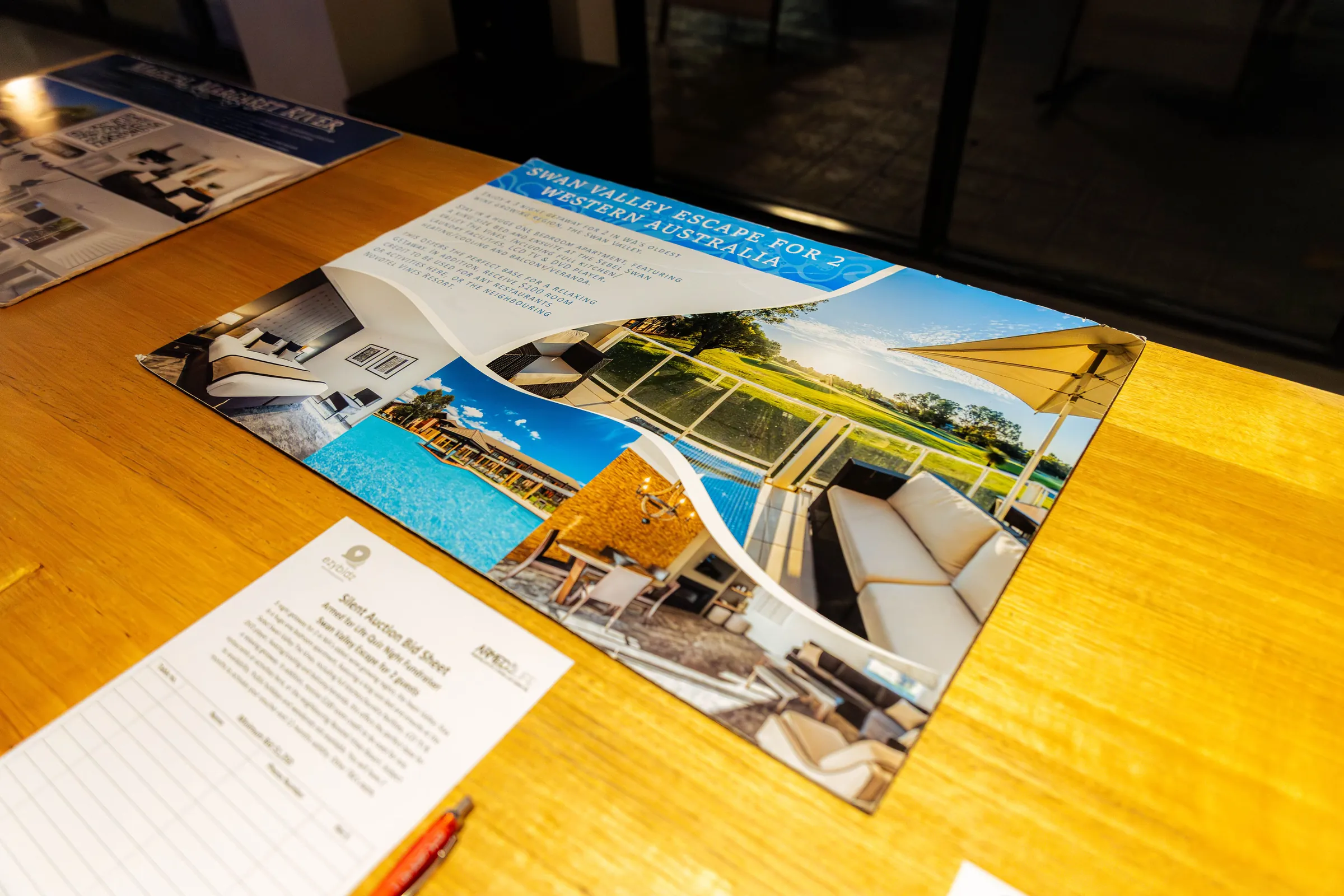 A silent auction sheet and a Bali escape flyer on a table at the Armed For Life quiz night at The Hall, The Camfield, Burswood.