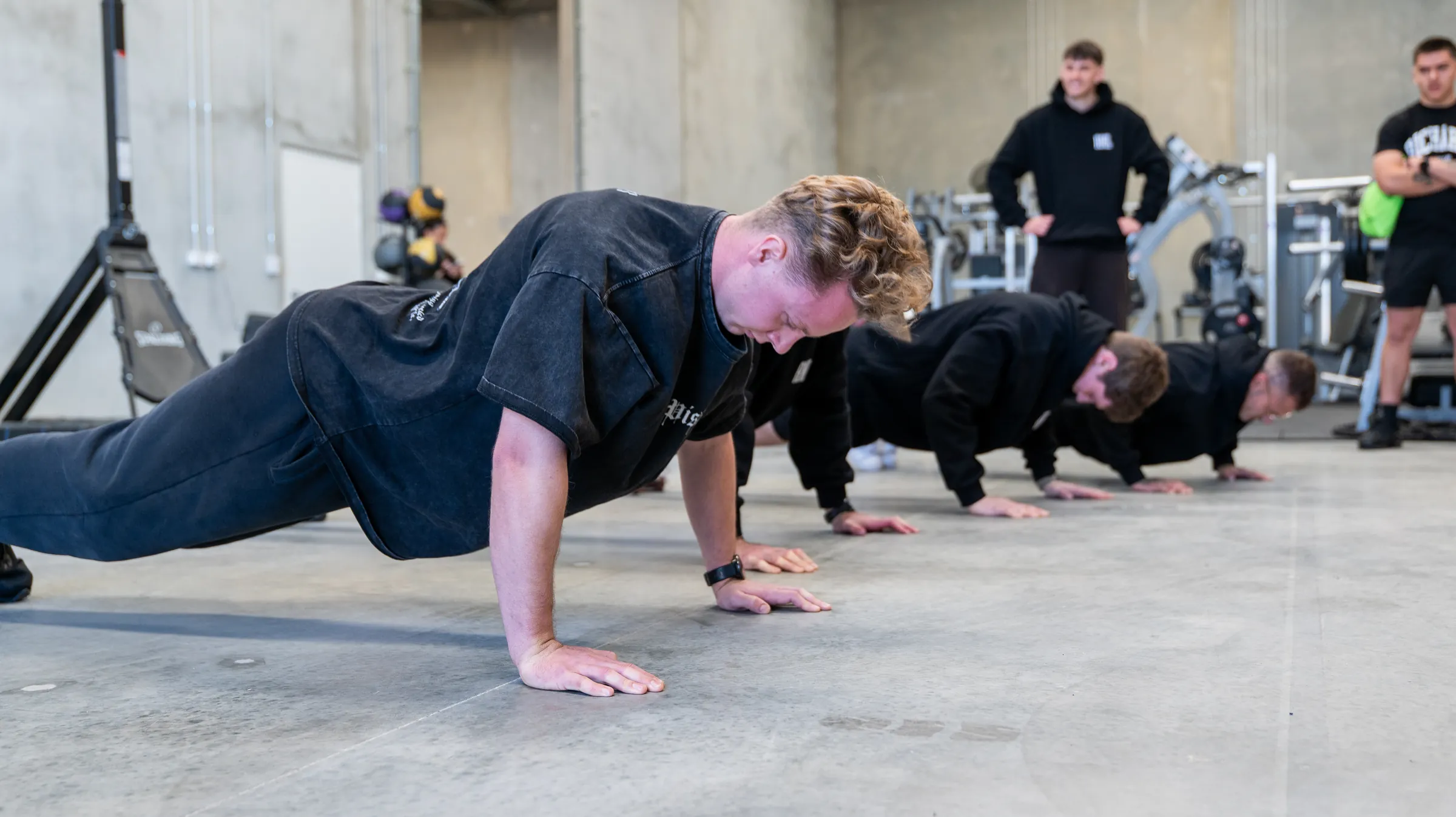 A trainer leading a group through push-ups in a Perth gym, personal brand photography by Growth Concept Media.