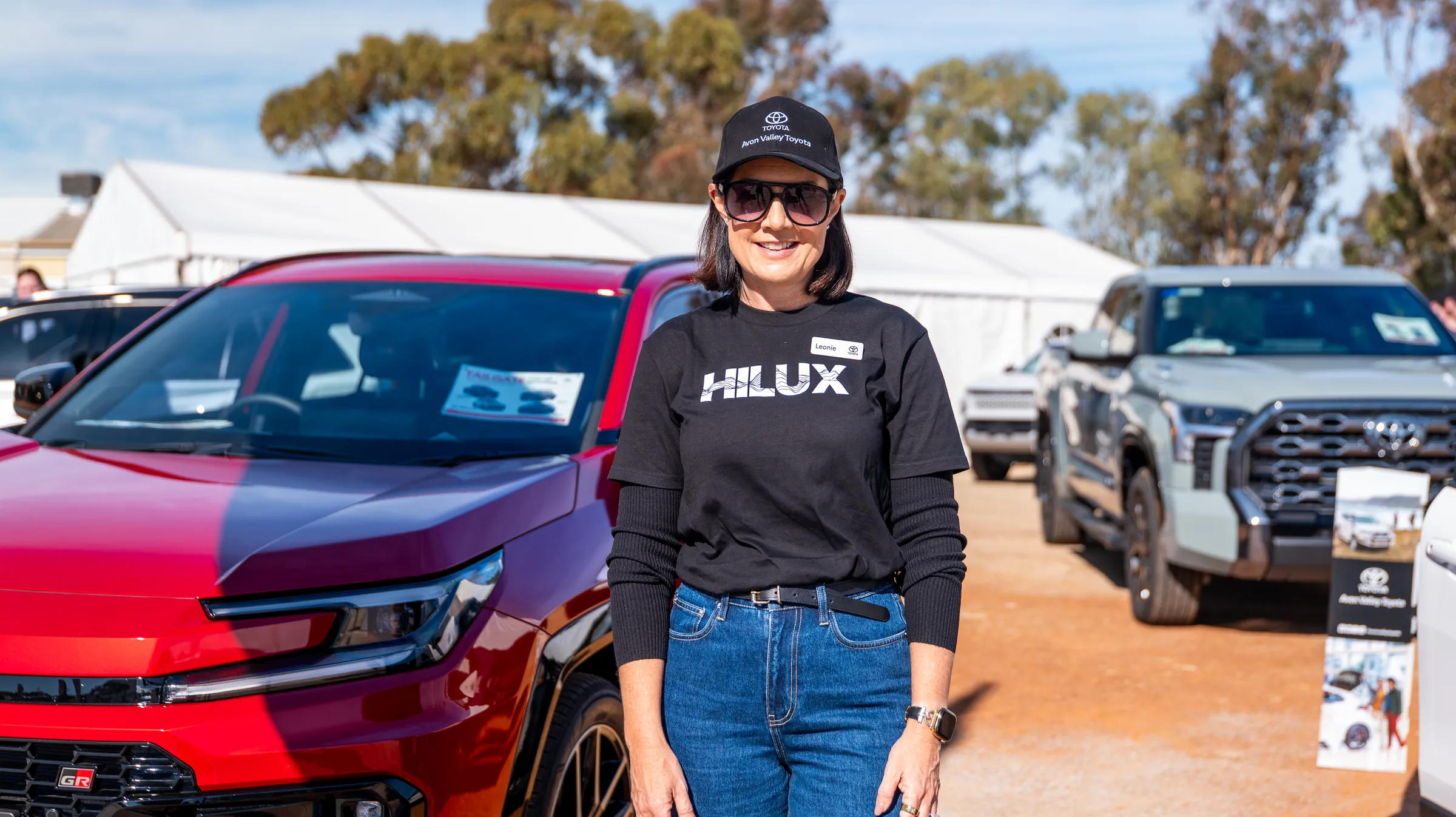 A woman photographed beside a Hilux at an outdoor display by Growth Concept Media.