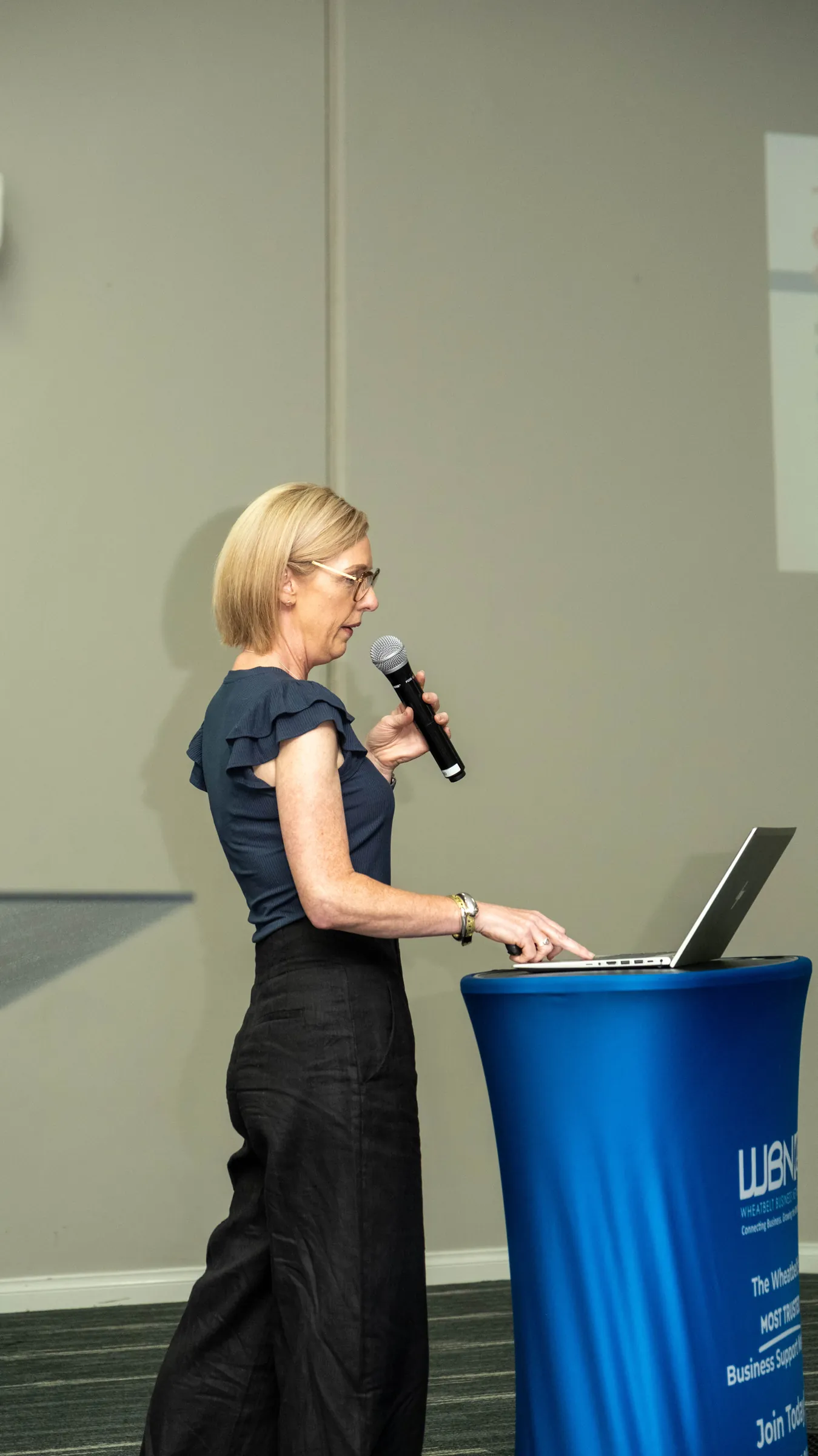 A woman speaking into a microphone at a lectern.