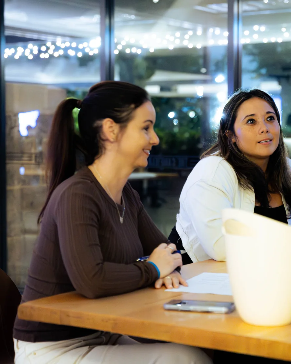 Two women at a table with notes, talking through a plan, photographed by Growth Concept Media in Perth. Two women at a table with notes, talking through a plan, photographed by Growth Concept Media in Perth.