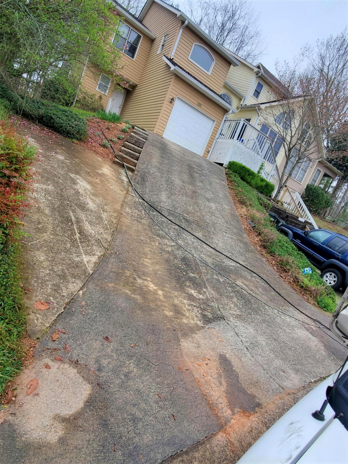 Concrete driveway darkened with dirt and organic staining before pressure washing