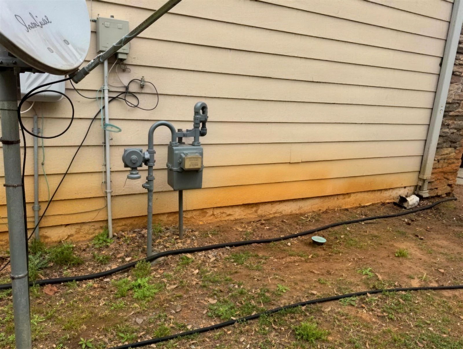Utility wall behind gas meters covered in dirt and mildew before washing