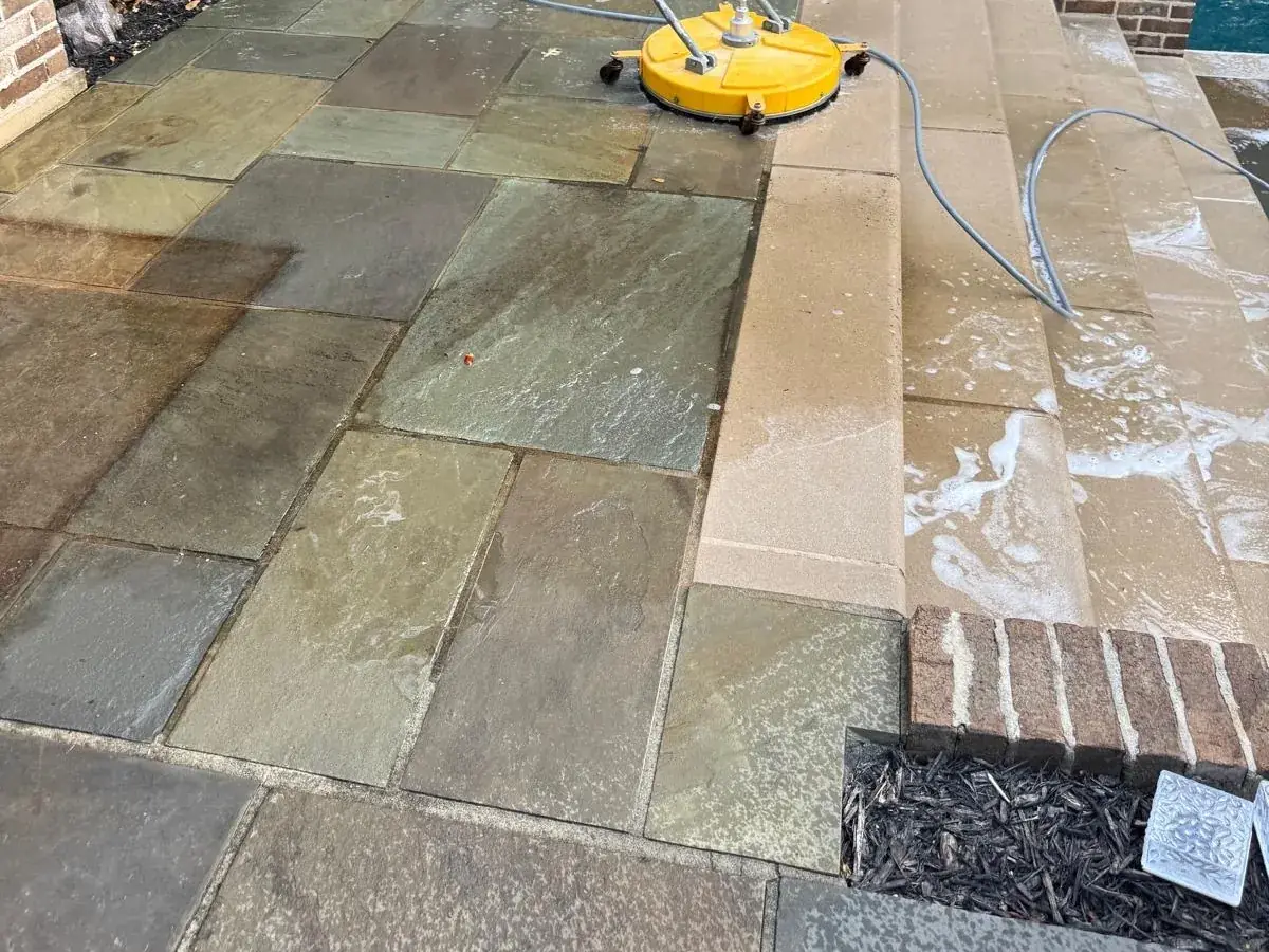 Bluestone patio mid-clean, with dark dirty stone beside stone the surface cleaner has already passed over