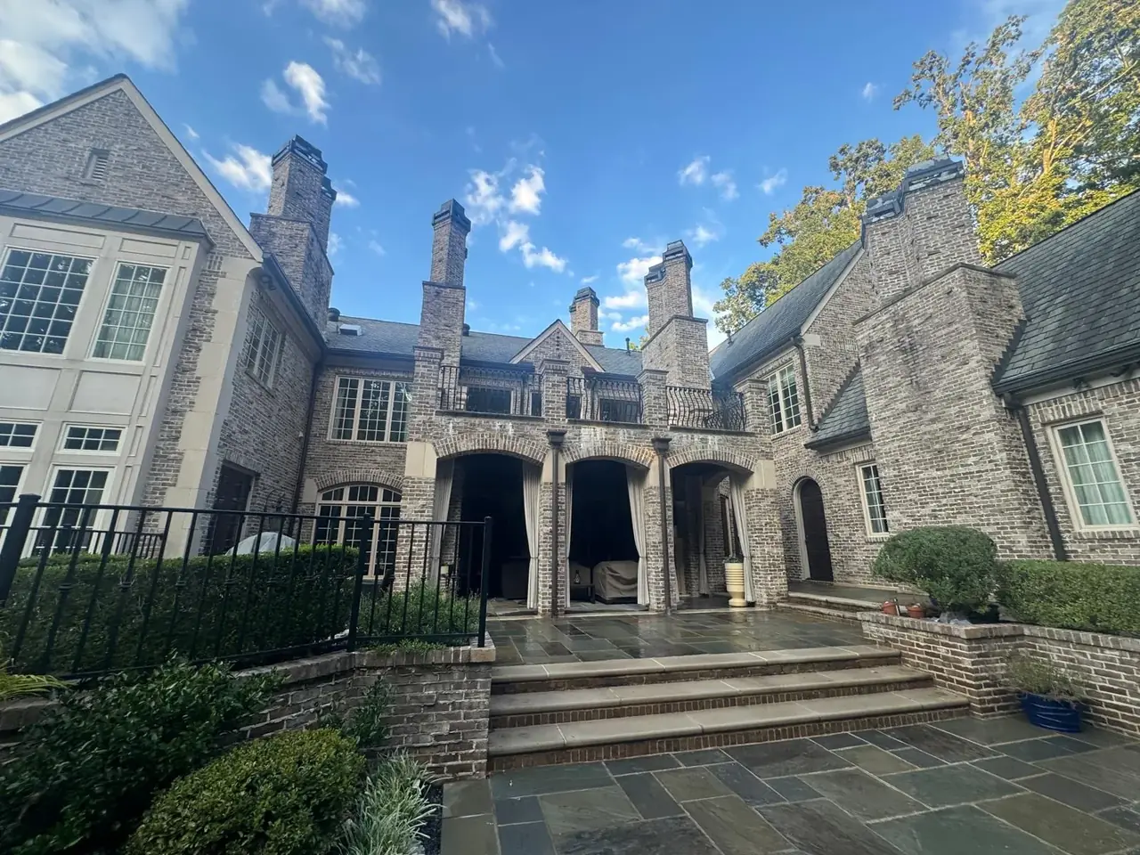 Clean bluestone terrace and stone steps under the brick arches of an estate home