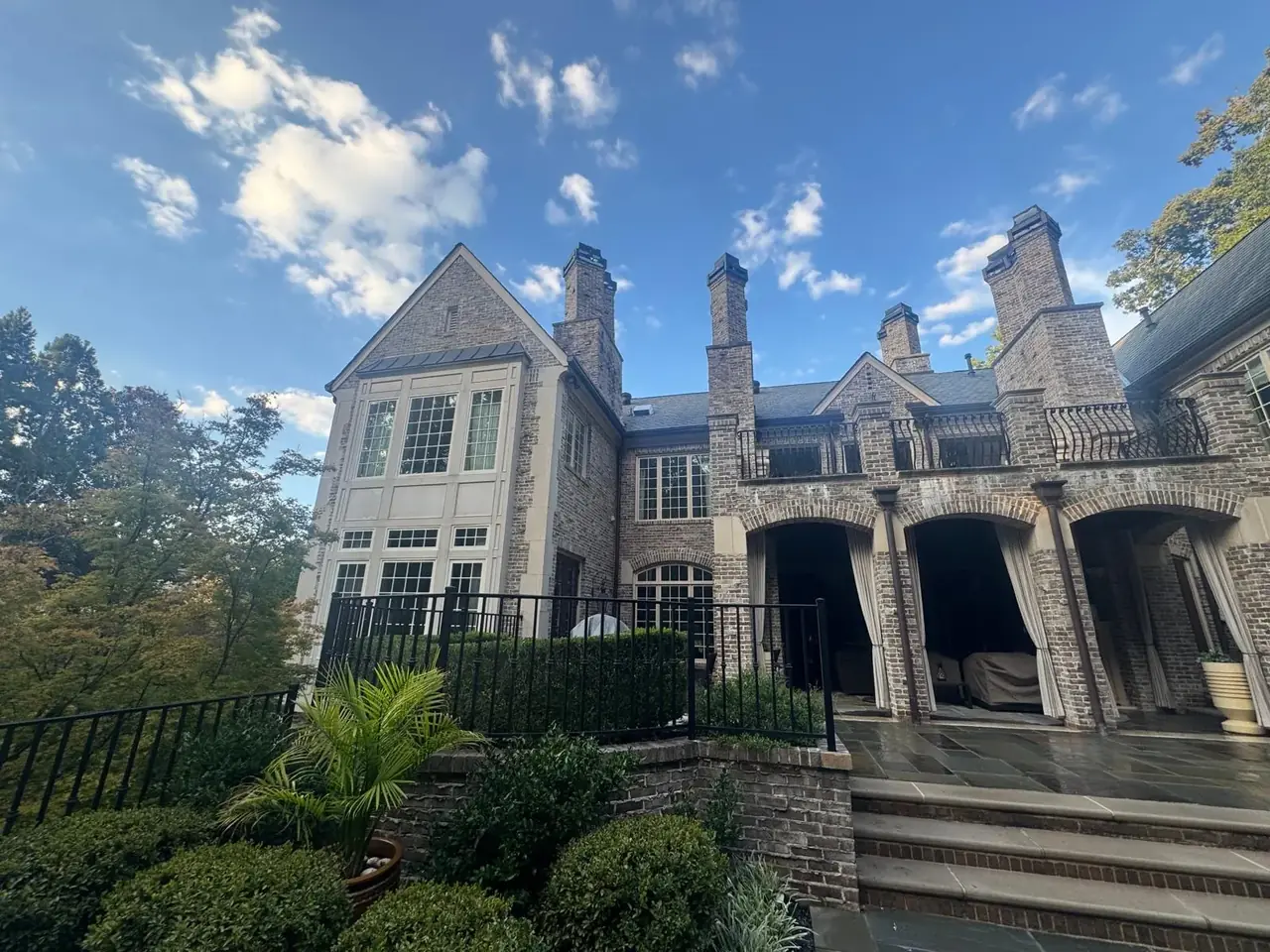 Rear elevation of a brick estate home with tall chimneys, iron balconies and a bluestone terrace after cleaning