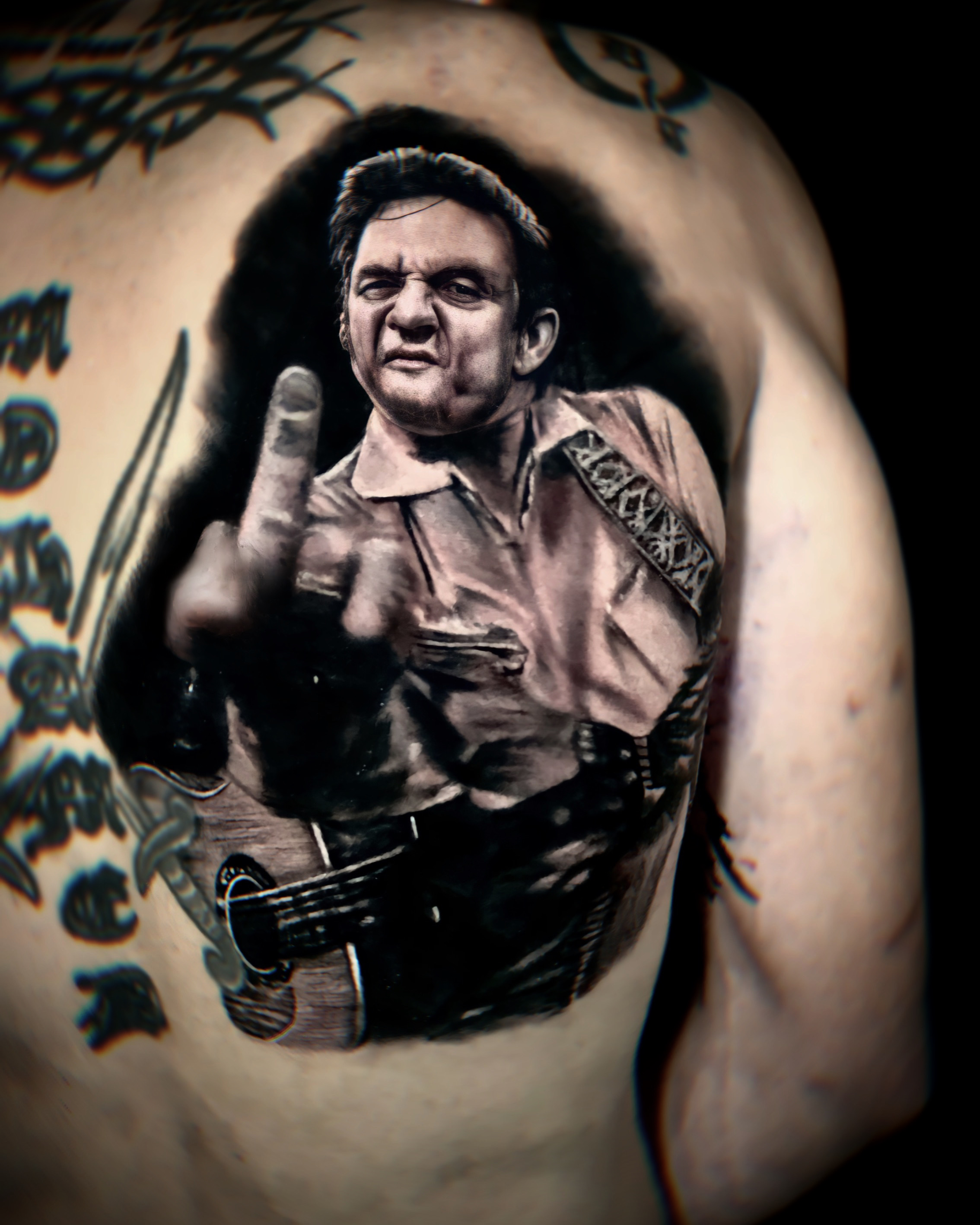 Black and grey Johnny Cash guitar portrait tattoo by Chucky Holden.